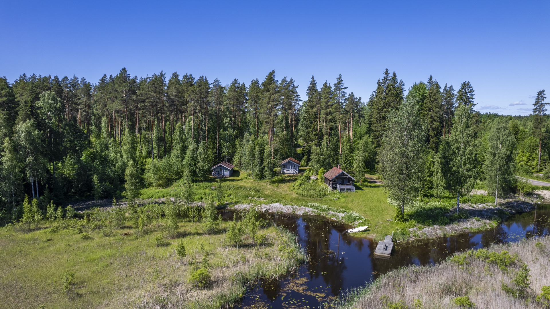 rannassa kolme mökkiä
