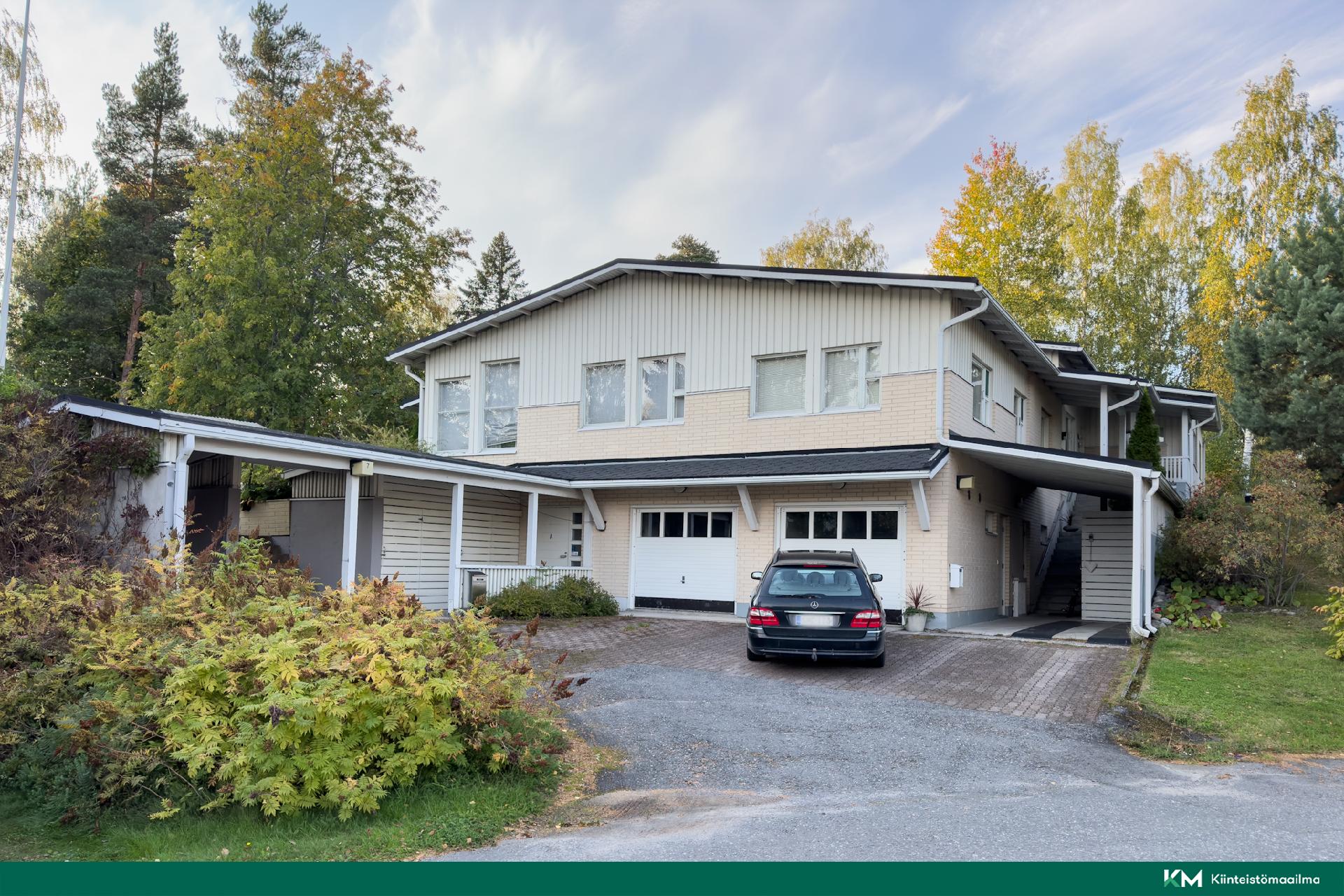 Julkisivu kadultapäin. Edessä autokatos, myytävän huoneiston autotalli vasemmalla puolella