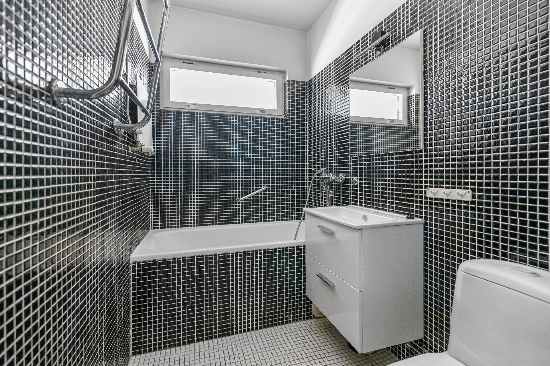 Laatoitettu kylpyhuone, jossa pyyhekuivain.