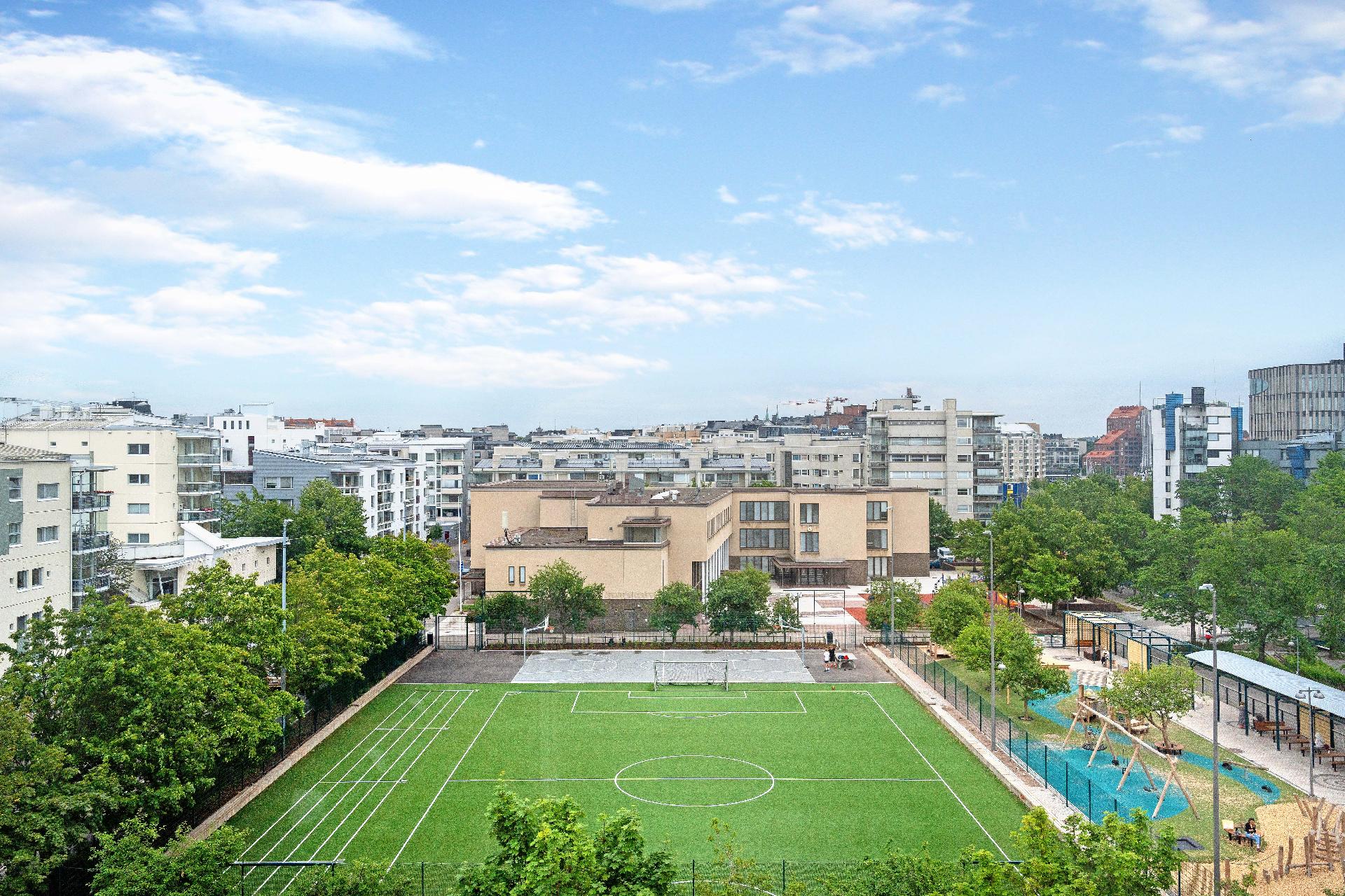 Näkymä makuuhuoneen ikkunasta. Jalkapallokentän takana ala-asteen koulu.