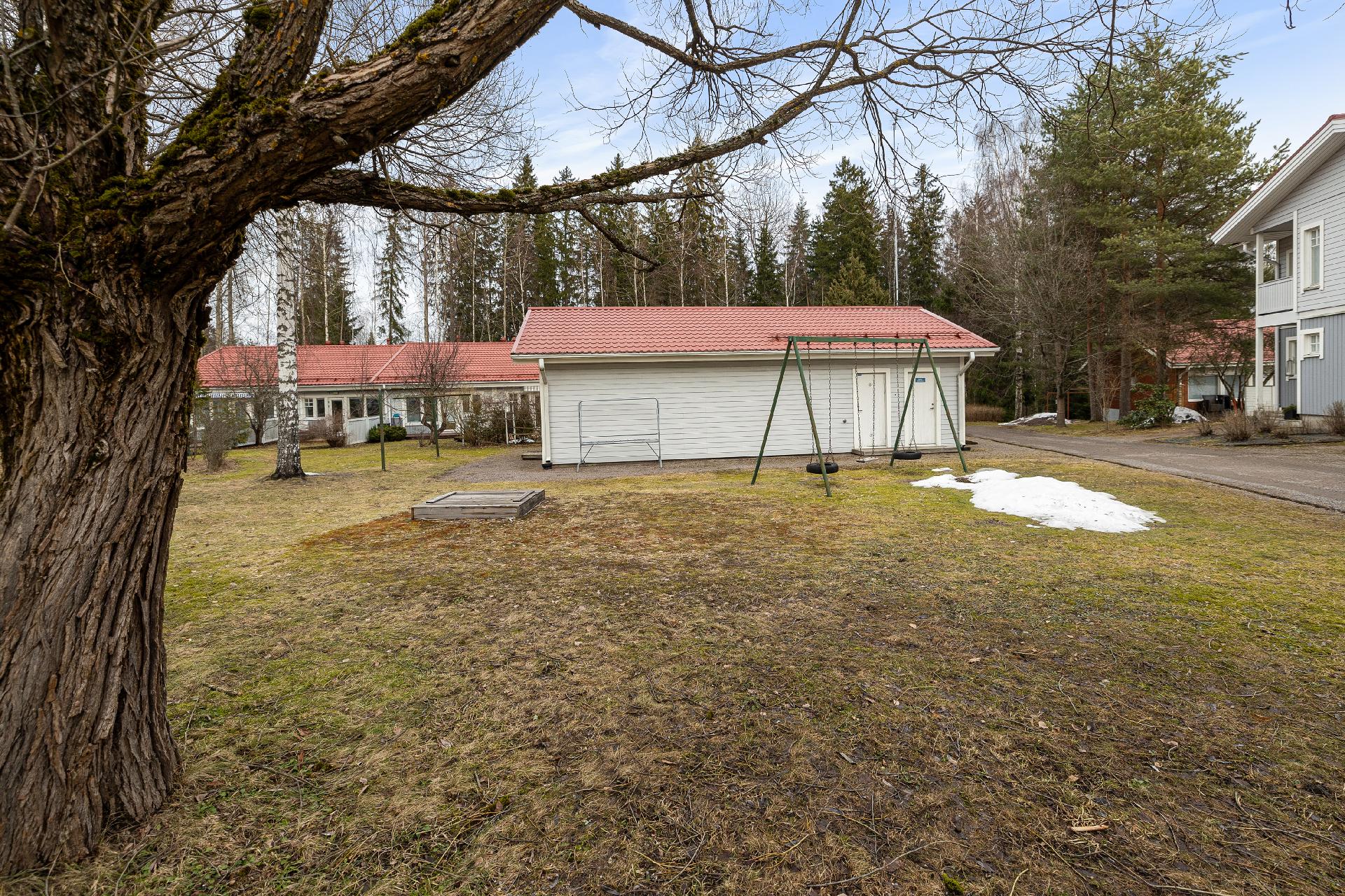 Yhtiön pihaa, varastorakennus ja keinut.