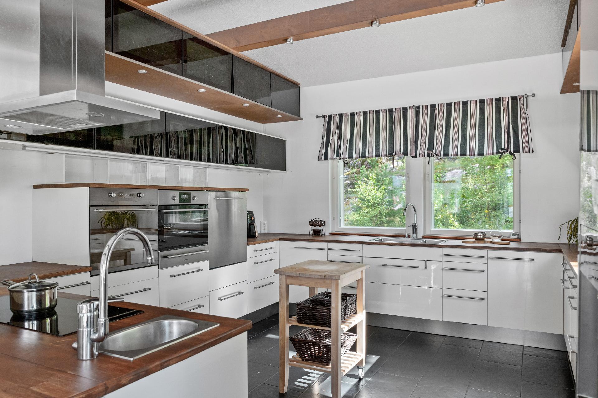 Moderni iso keittiö monipuolisine laitteineen kutsuu kokkaamaan