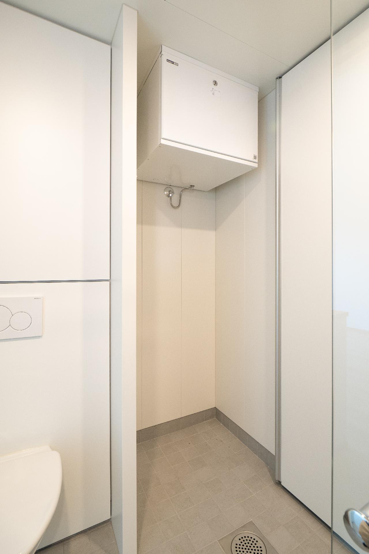 Kylpyhuoneessa ovellinen kaappi pesutornille