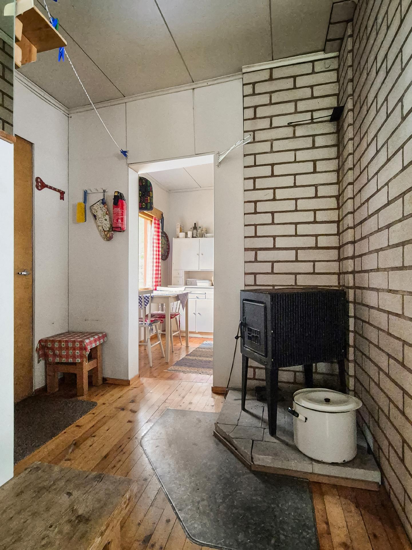 Toinen sisäänkäynti päärakennuksen takapuolelle, jossa kamiina ja kulku keittiöön.