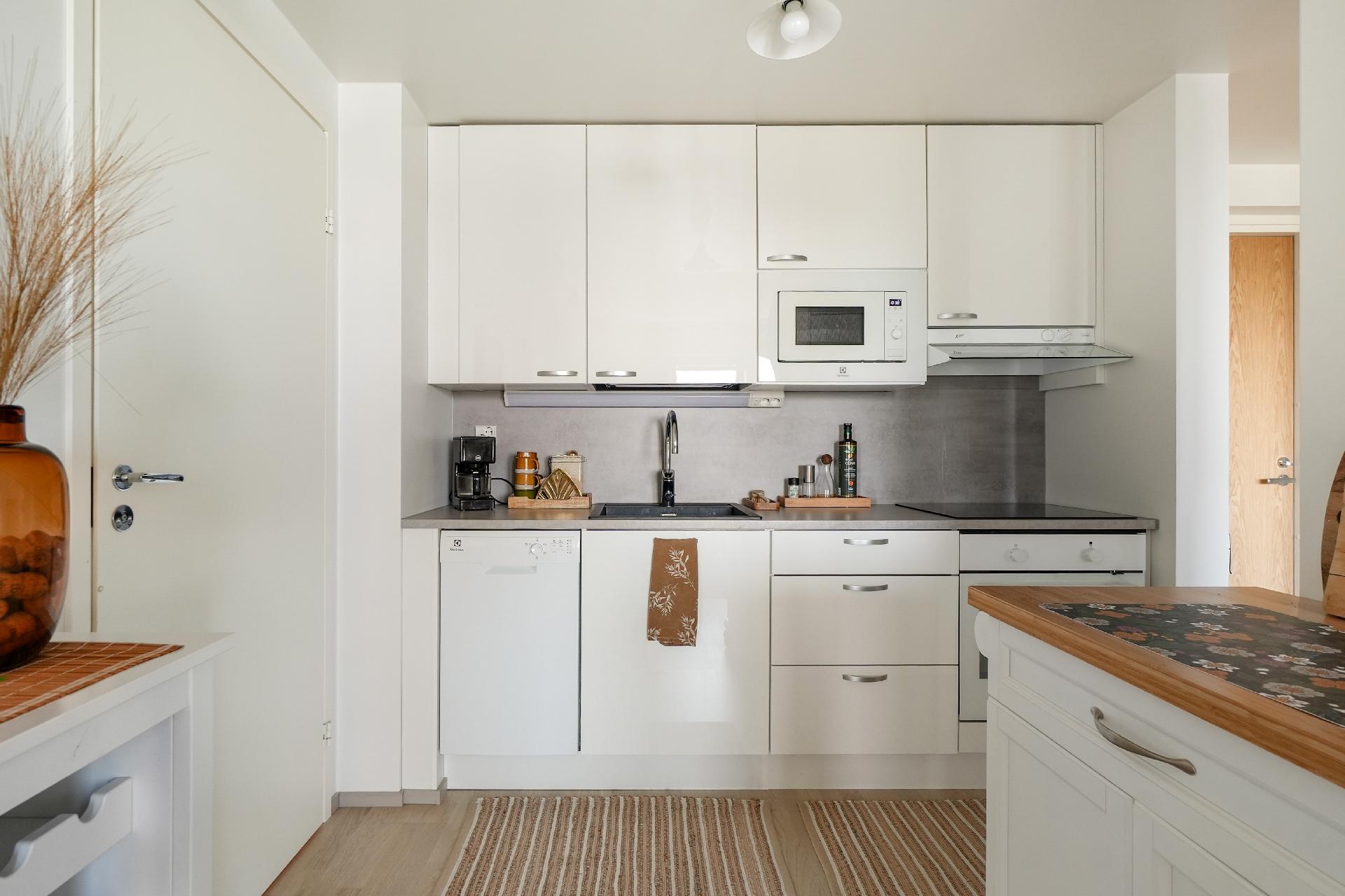 Tyylikkäässä keittiössä on kaikki tarvittava. Tila avautuu osittain olohuoneeseen.