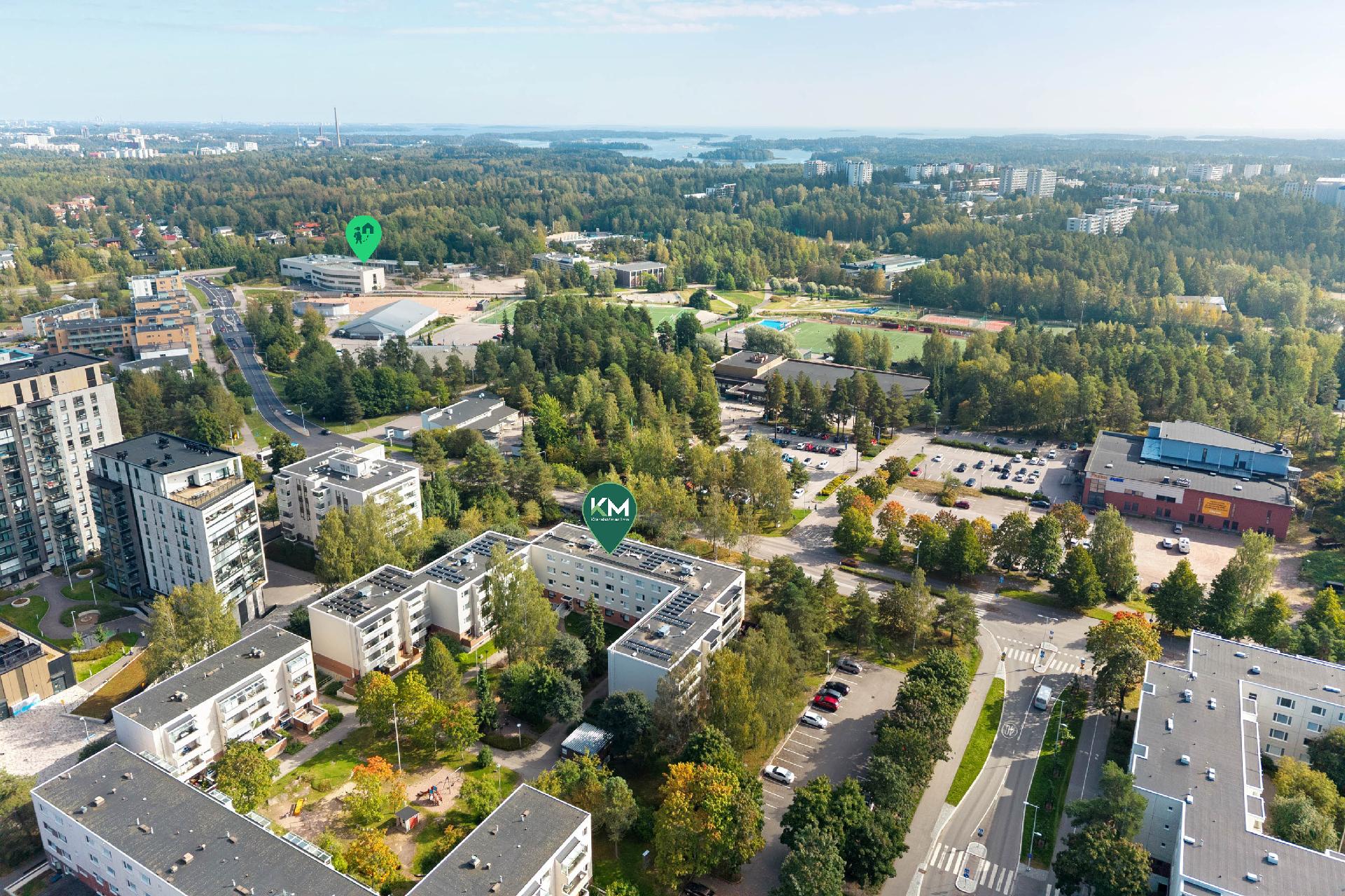 Taustalla päiväkoti ja koulu, urheiluhalli- ja puisto.