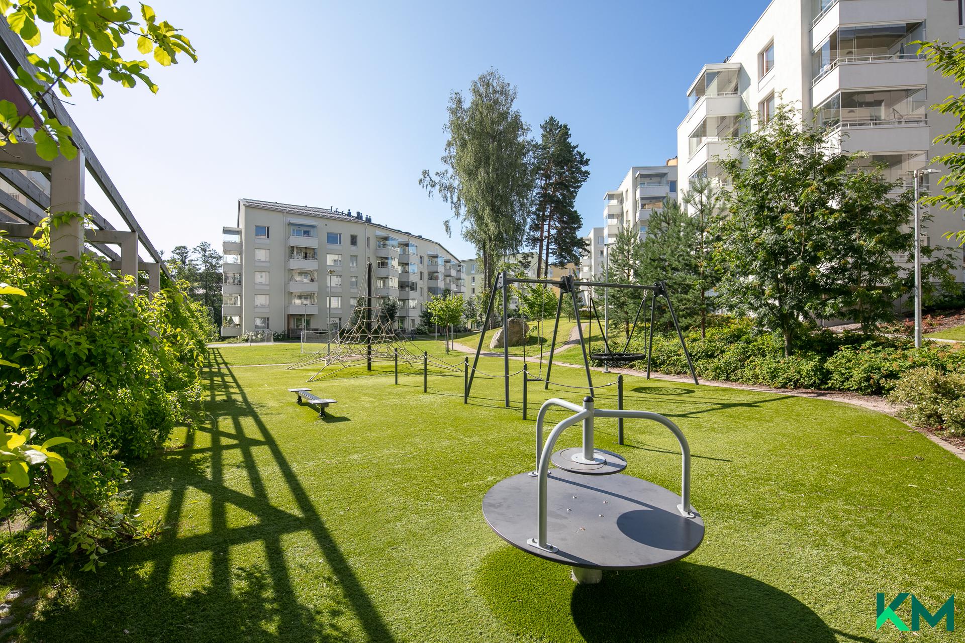 Talojen keskellä vehreä leikkipaikka