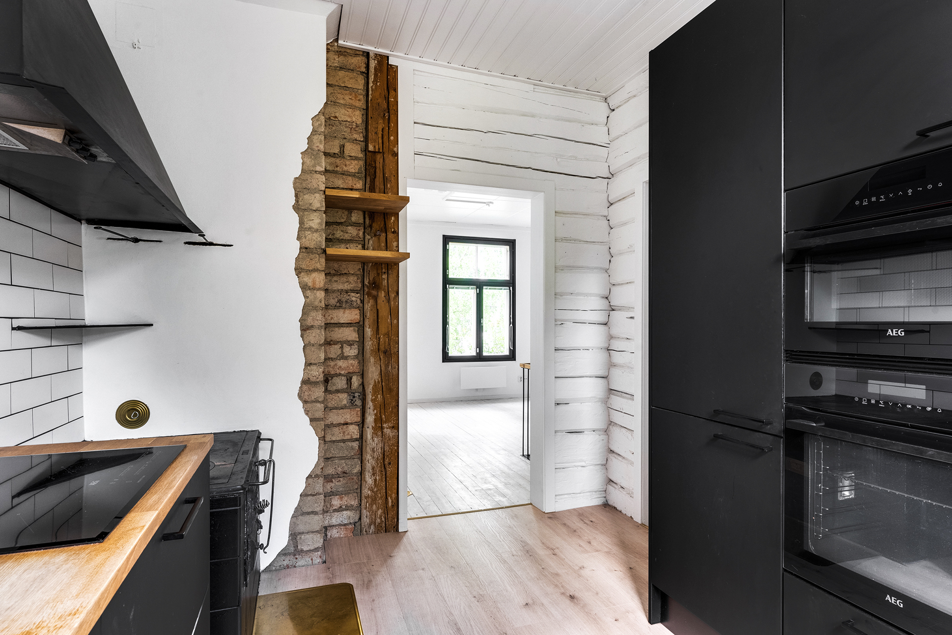 Kaunis tehosteseinä, jossa näkyy vanhaa hirttä ja tiiltä.