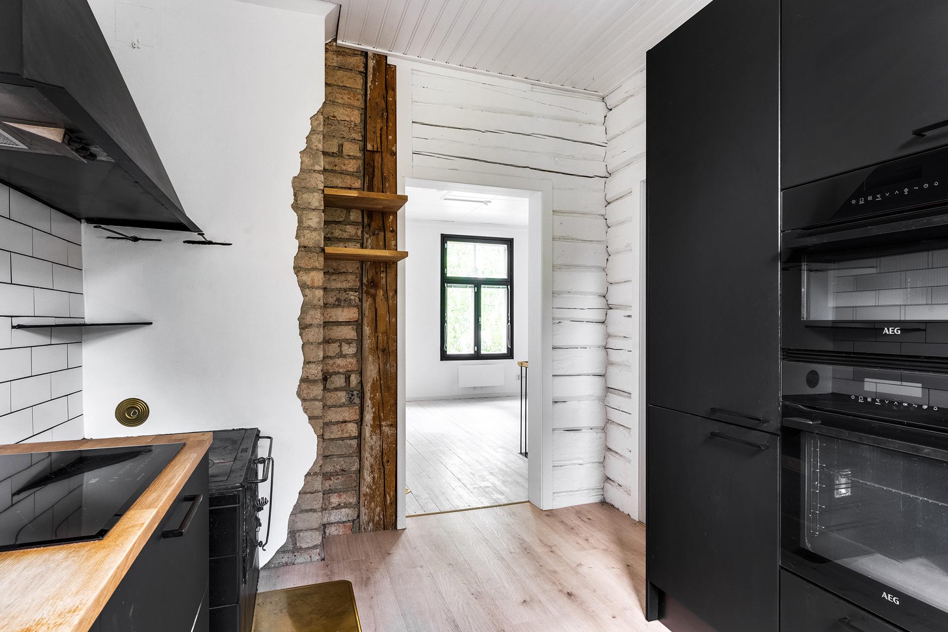 Kaunis tehosteseinä, jossa näkyy vanhaa hirttä ja tiiltä.