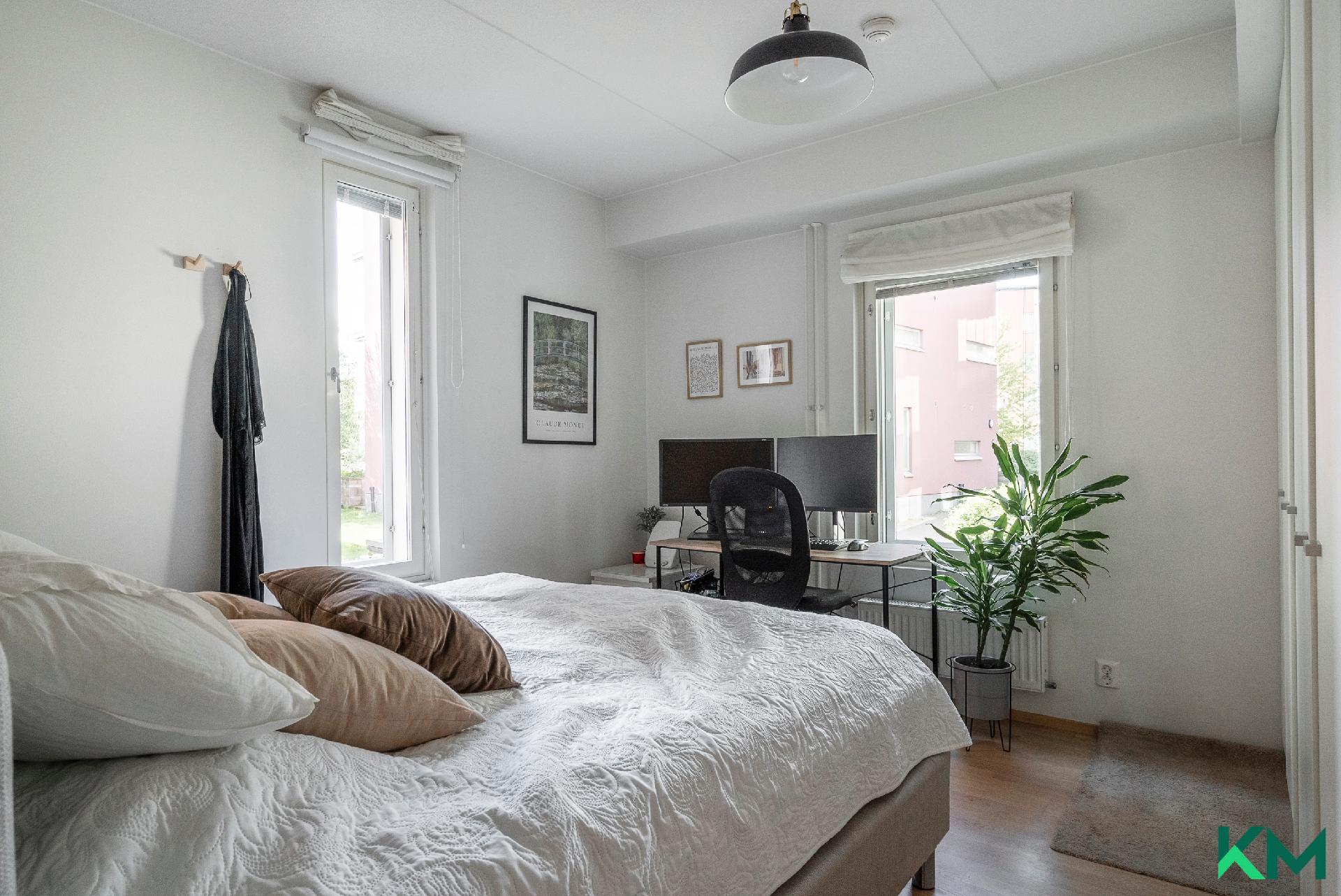 Tilava makuuhuone jossa ikkunat kahteen ilmansuuntaan