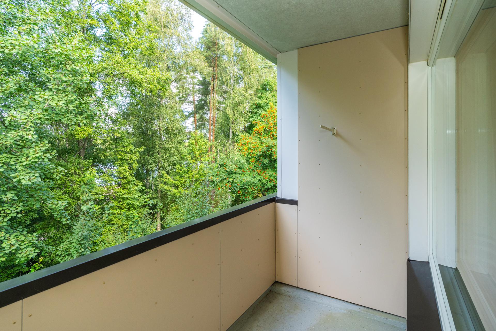 Parvekkeelta pilkottaa järvi puiden välistä.