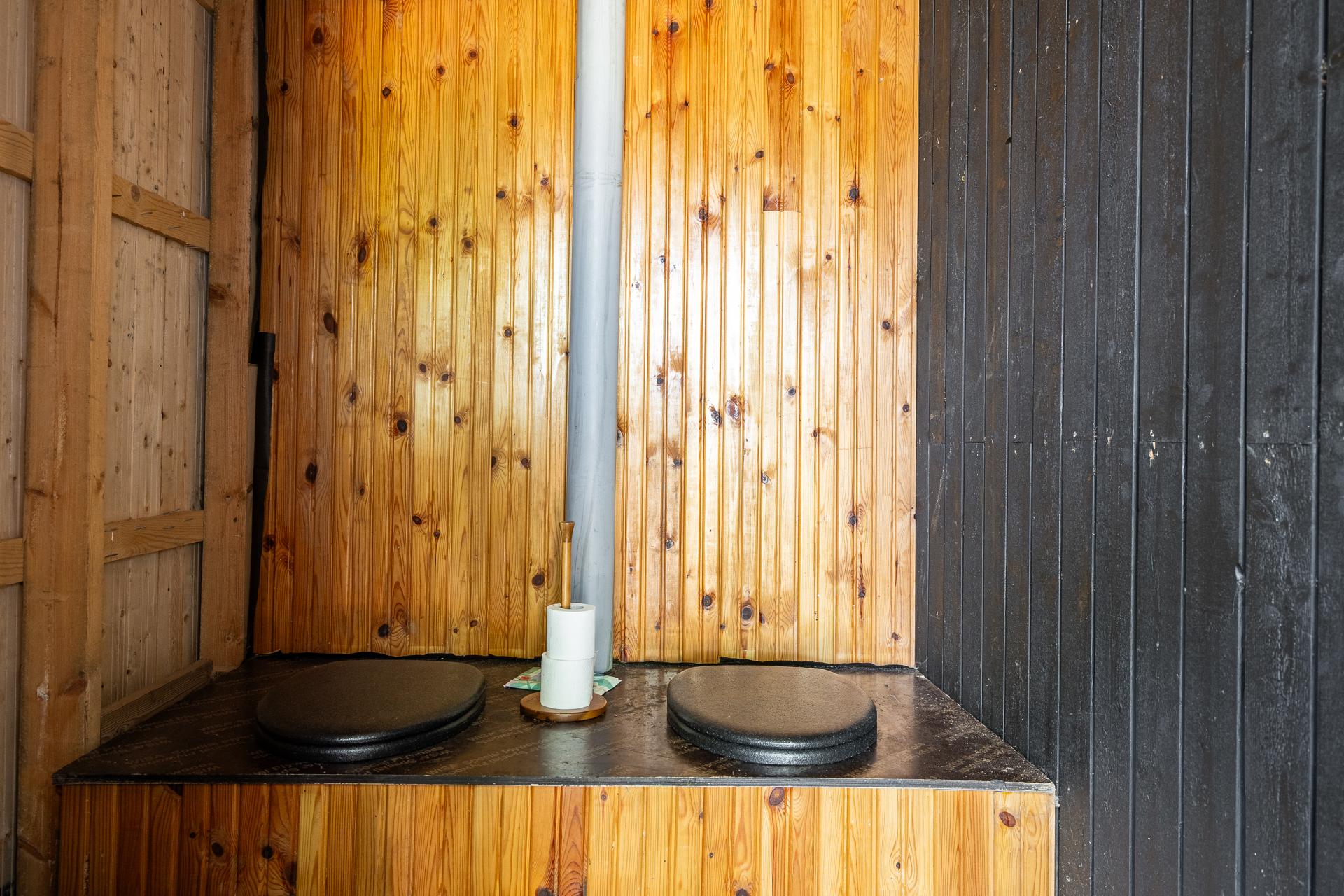 Kahden istuttava puucee vierastalon yhteydessä