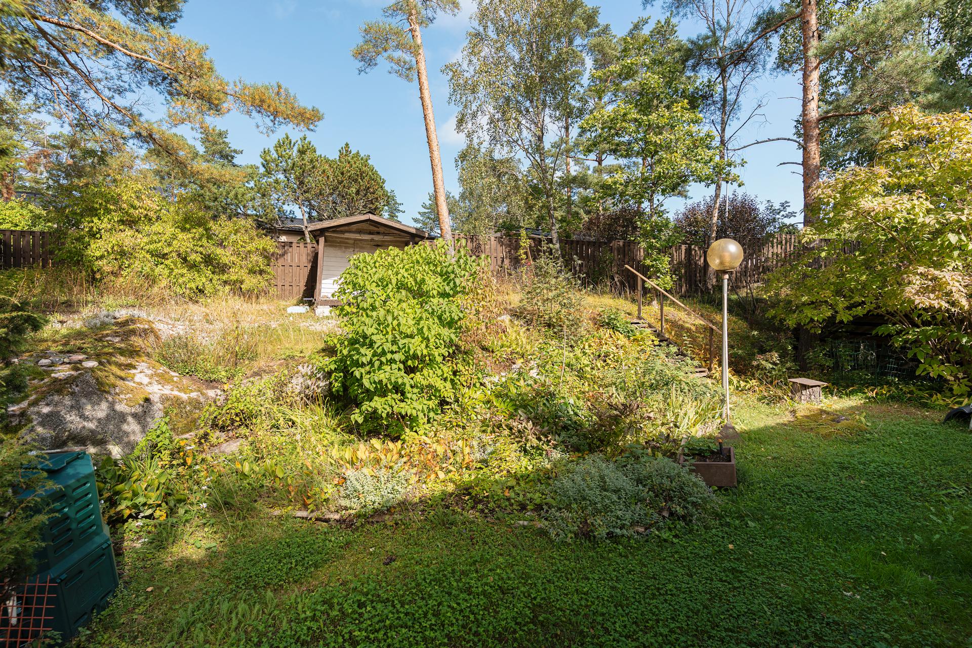 Takapihalla on runsaat istutukset ja leikkimökki