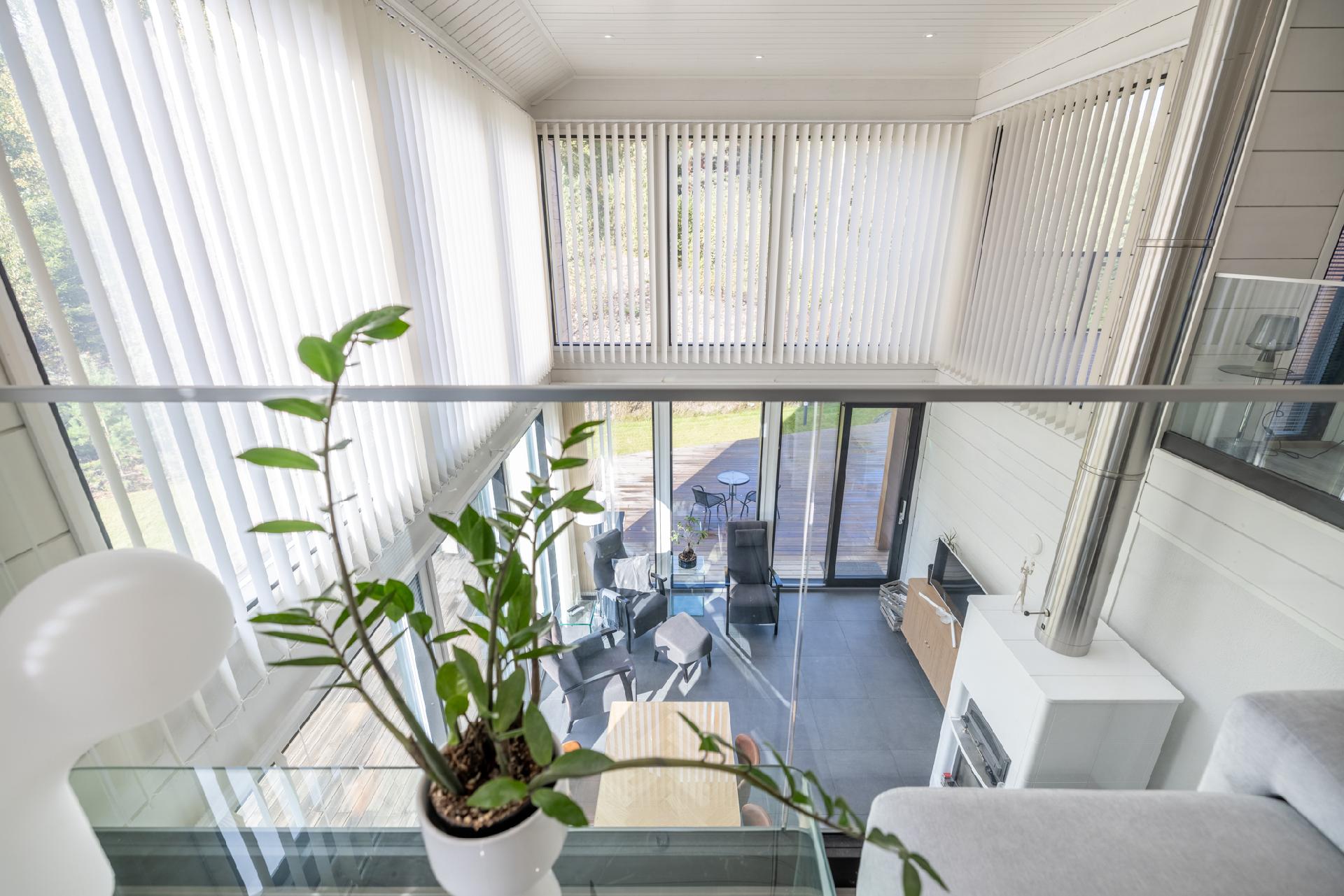 Yläkerran aulamaisesta oleskelutilasta avautuu näkymä korkeaan olohuoneeseen.