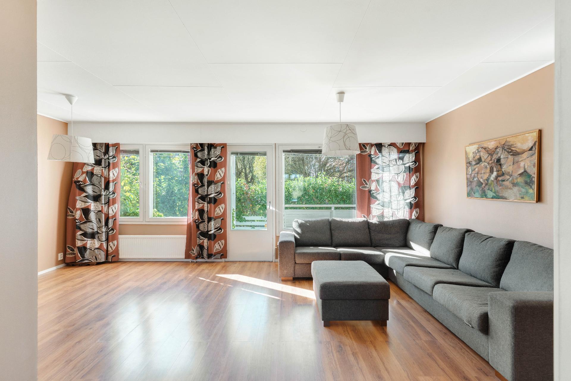 Olohuone on valoisa ja ikkunoista aukeaa näkymä takapihalle.