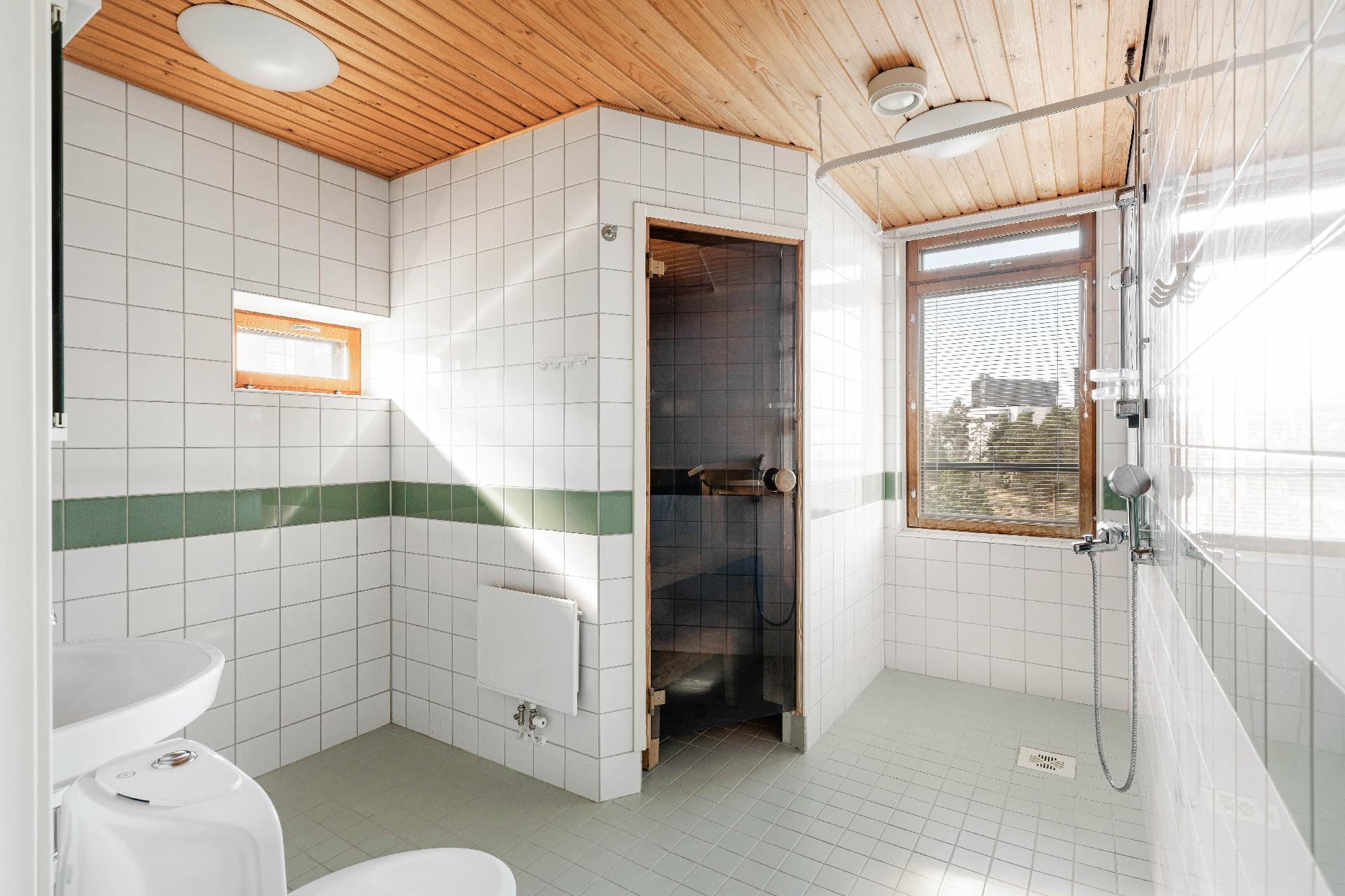 Kylpyhuoneessa oma sauna ja ikkunoista tulee sisään runsaasti luonnonvaloa.