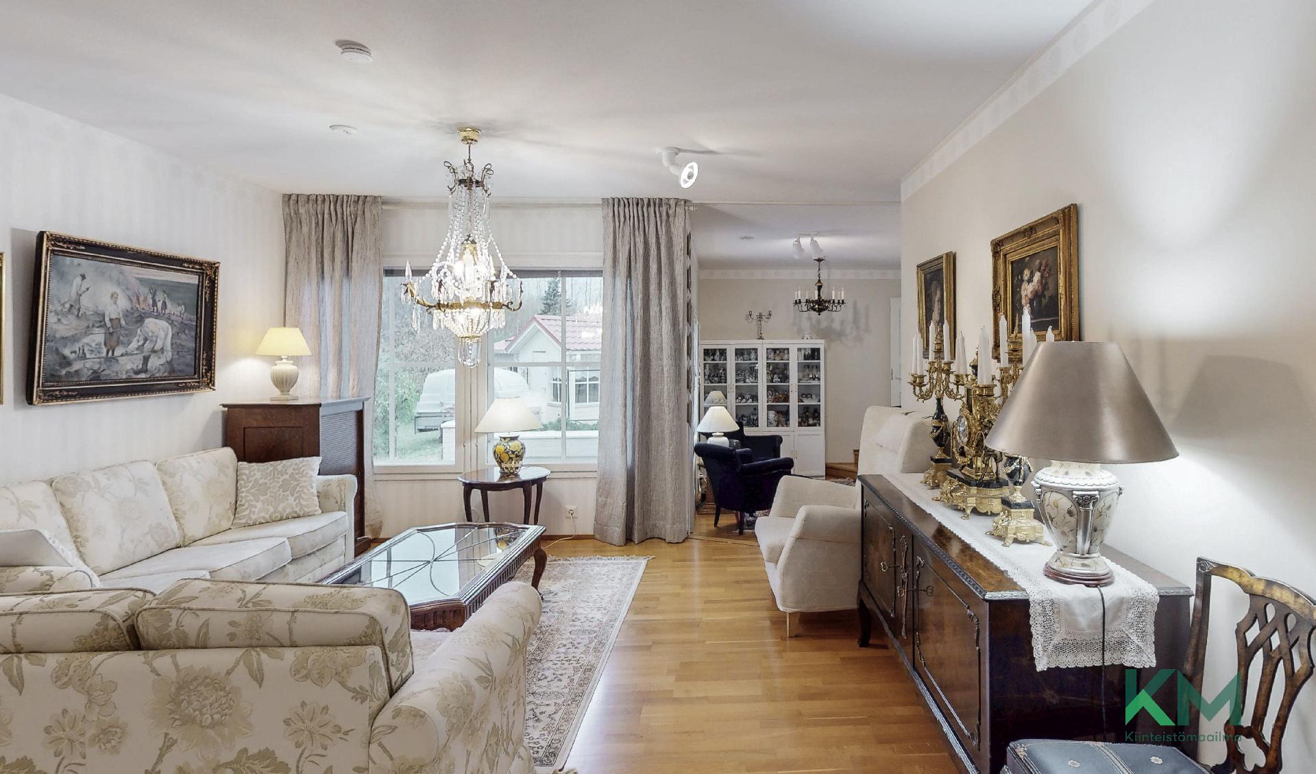 Olohuoneessa on hulppeasti tilaa ja olohuoneesta pääsee niin takkahuoneeseen, kun kirjastoon ja makuuhuoneisiin.