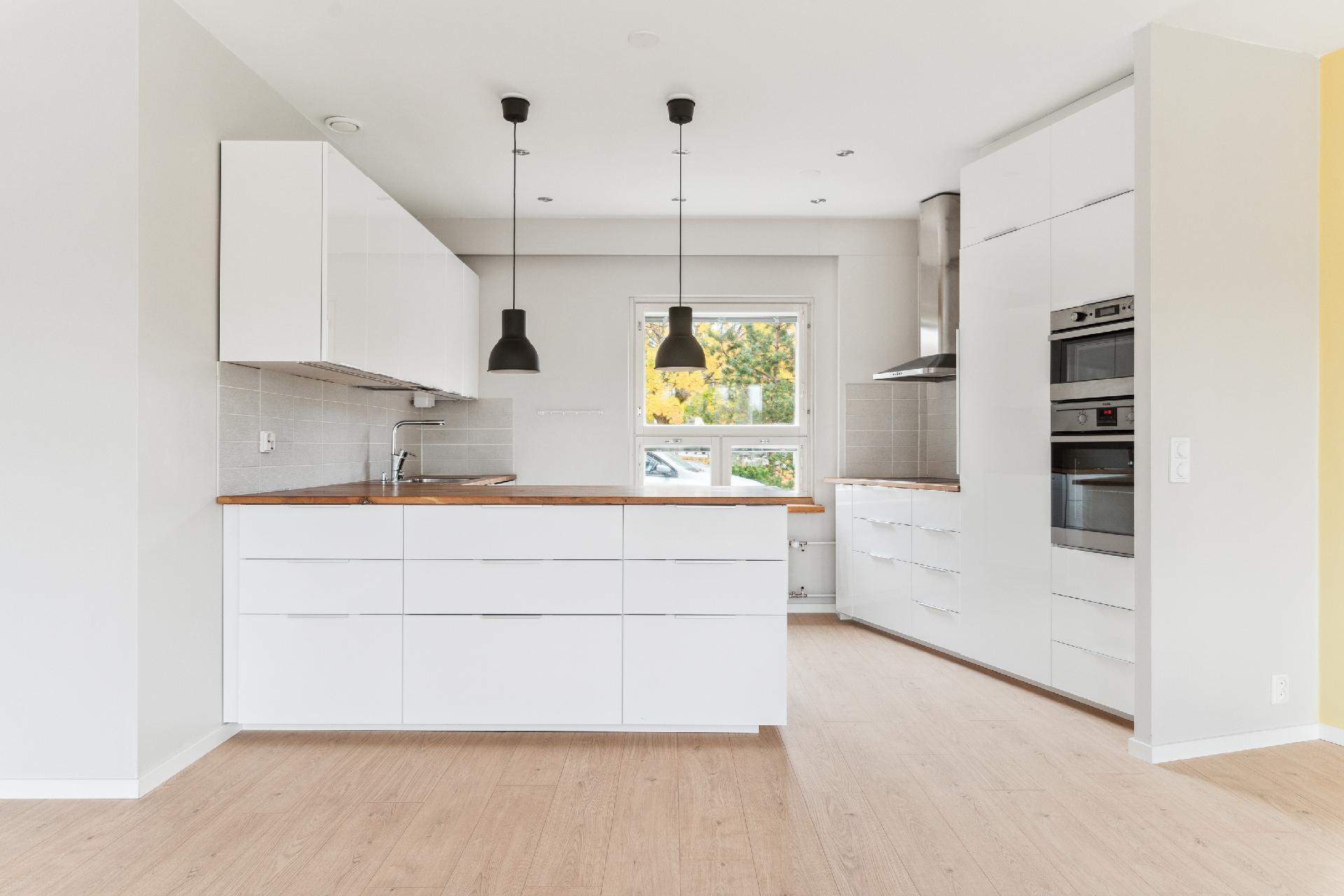 Tilava keittiö jossa runsaasti säilytys- ja työskentelytilaa