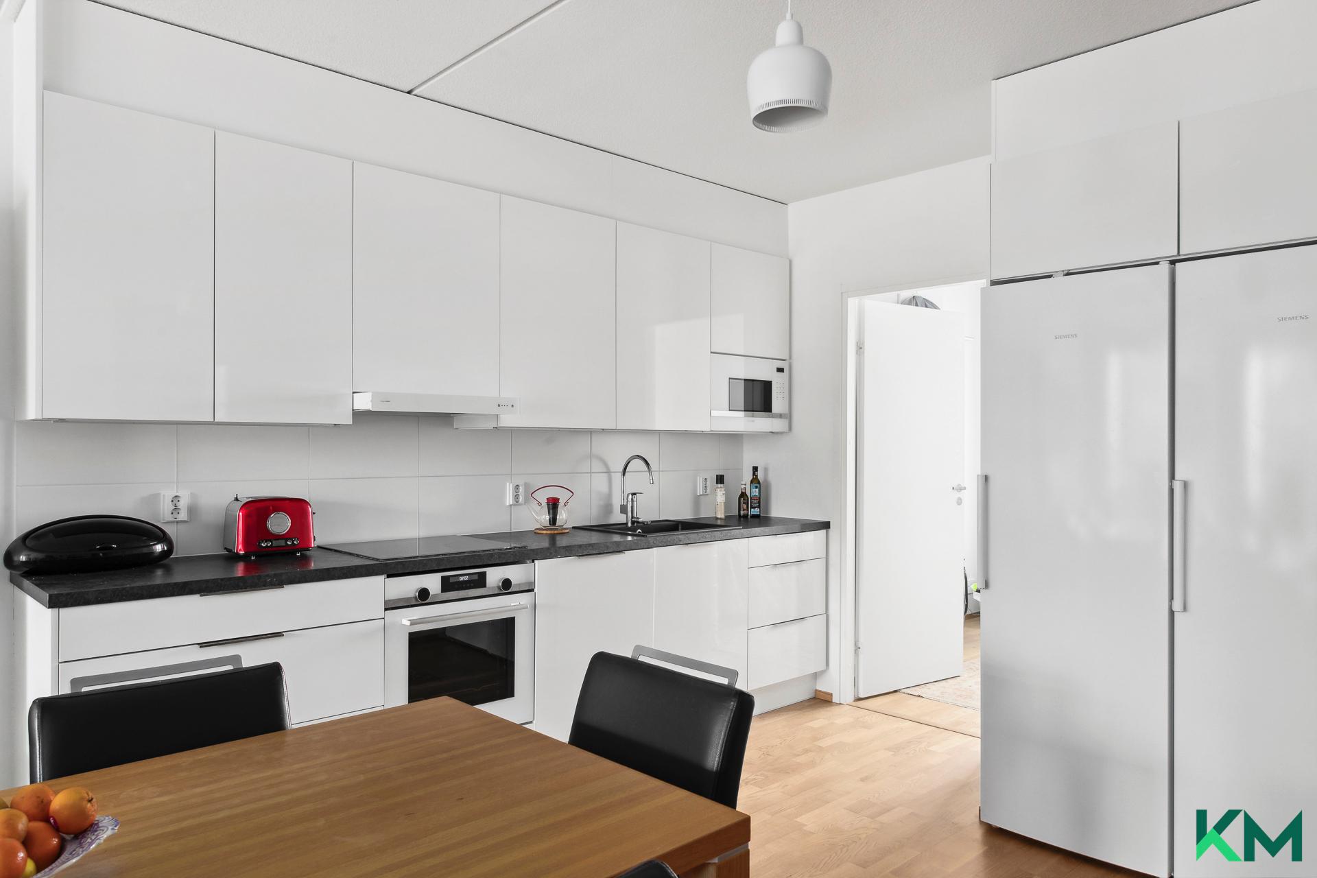 Linjakas avokeittiö, jossa koko korkeat jääkaappi ja pakastin