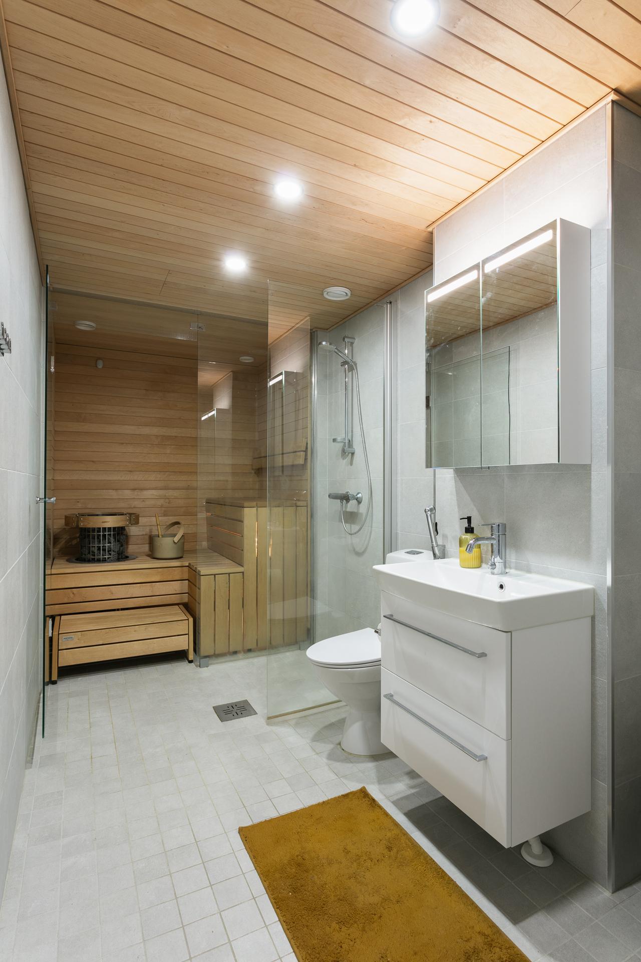 Tyylikas kylpyhuone jossa lasiseinäinen sauna