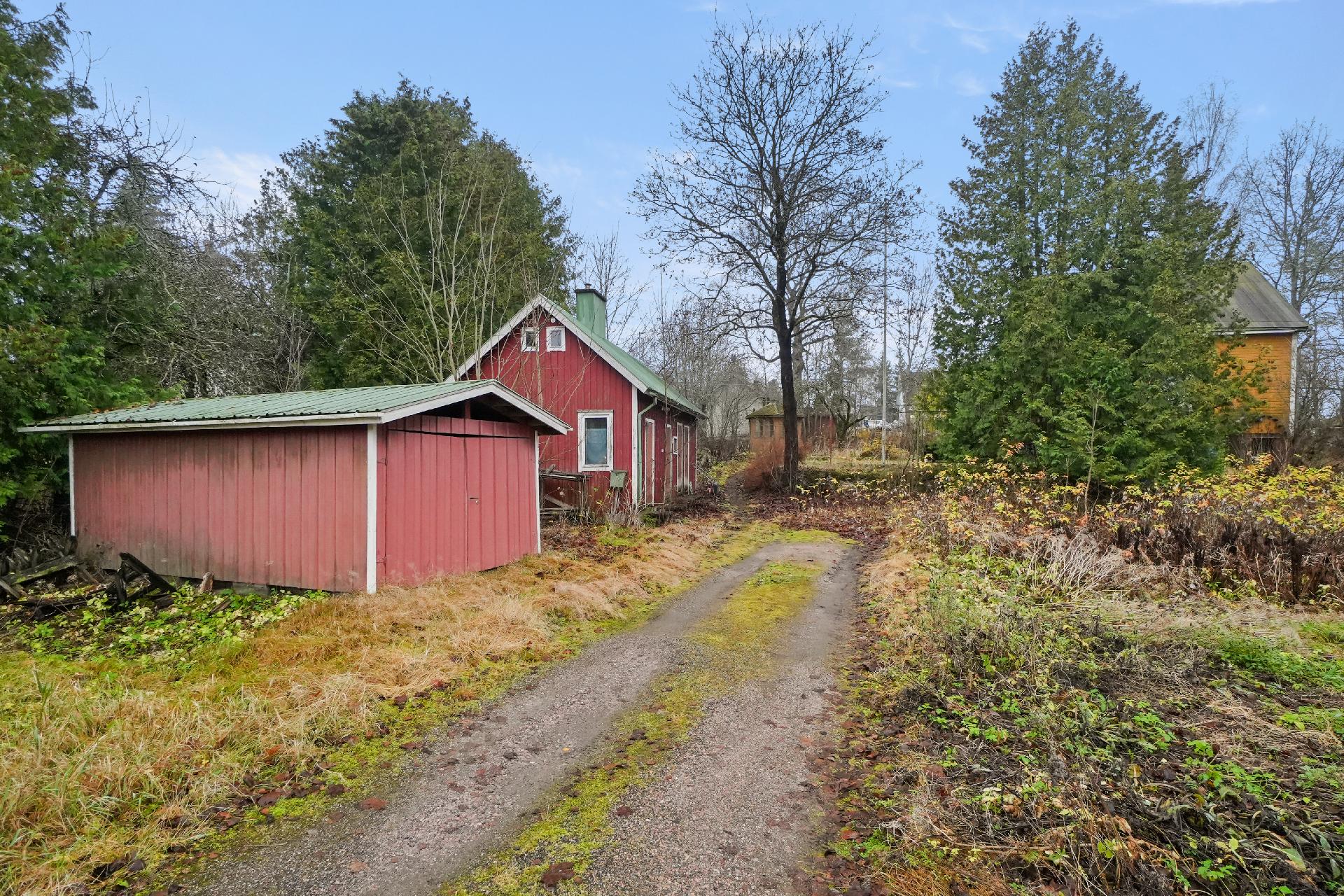 Pihapiirissä sijaitsee talousrakennus, peltinen autotalli ja huvimaja.