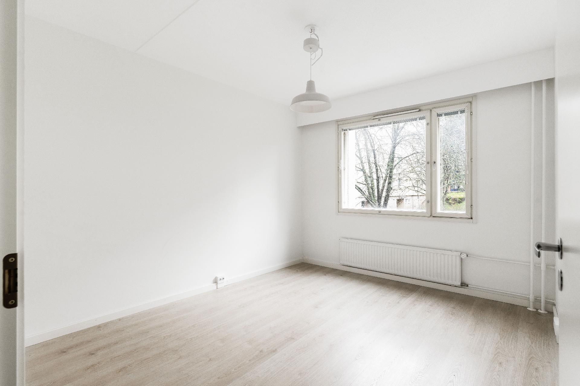 Tilava makuuhuone, josta kesällä vehreä näköala.