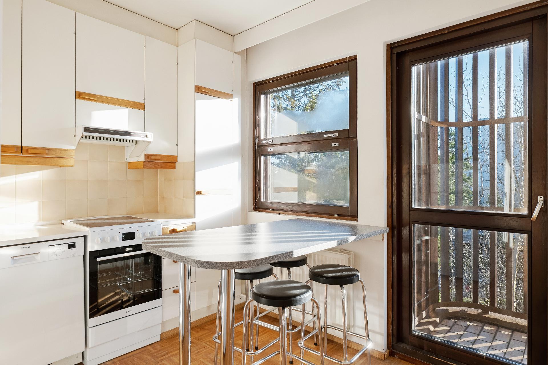 Keittiö on valoisa ja kodikas. Suuret ikkunat ja aamiaispöytä tekevät tilasta viihtyisän ja kutsuvan.