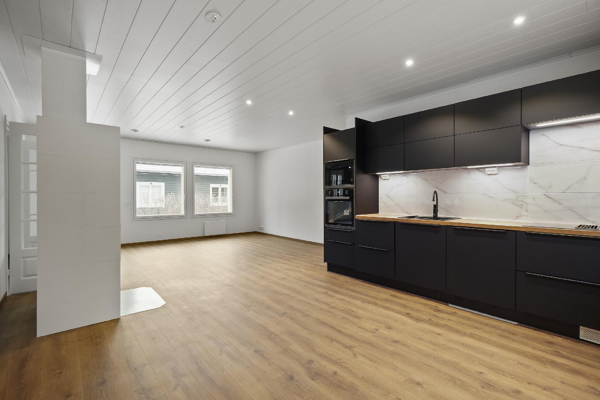 Näkymää kodinhoitohuoneen ovelta keittiöön ja olohuoneeseen.