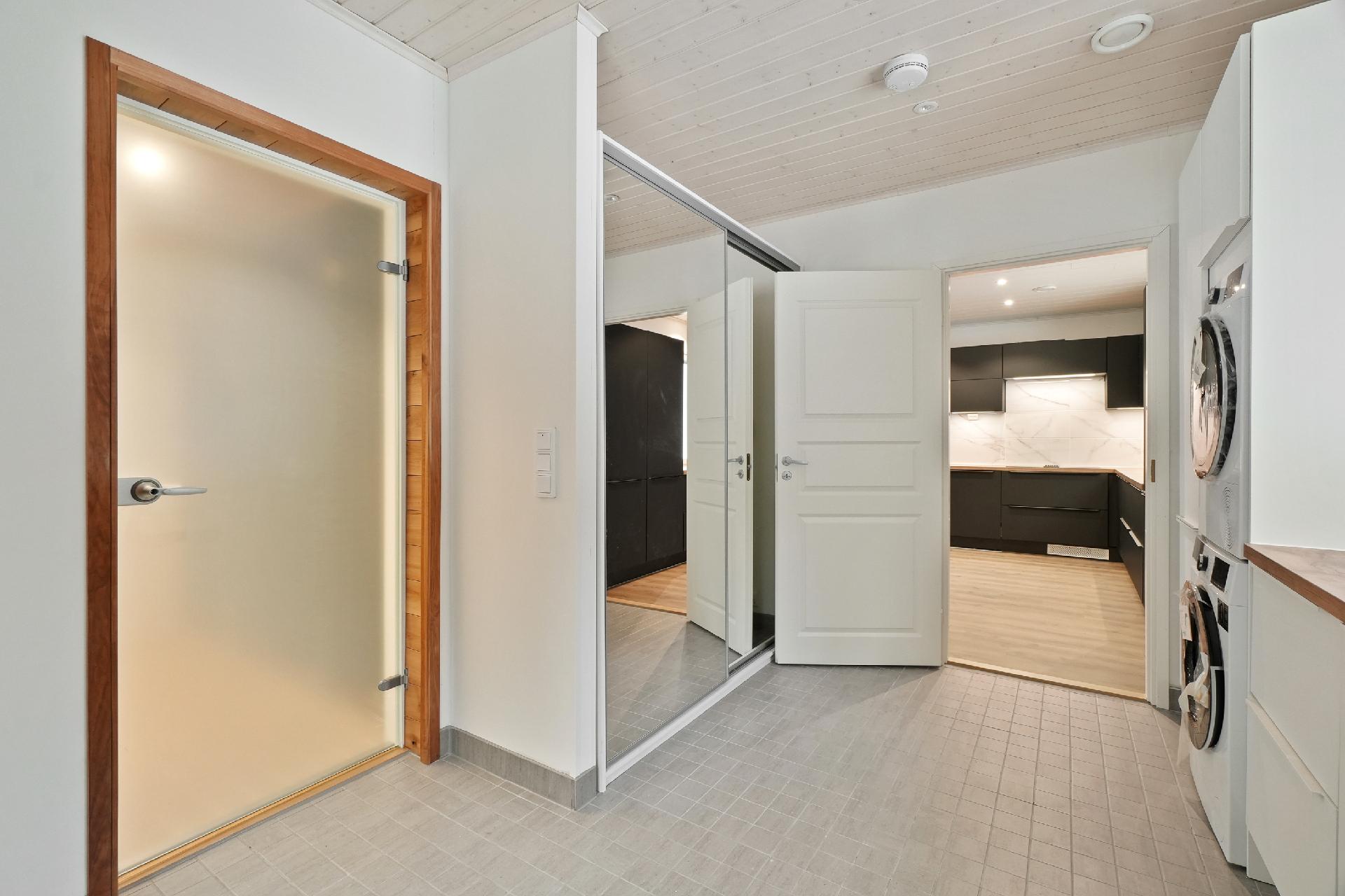 Oikealla pesutoni ja vastapäätä liukuovikaapistot.