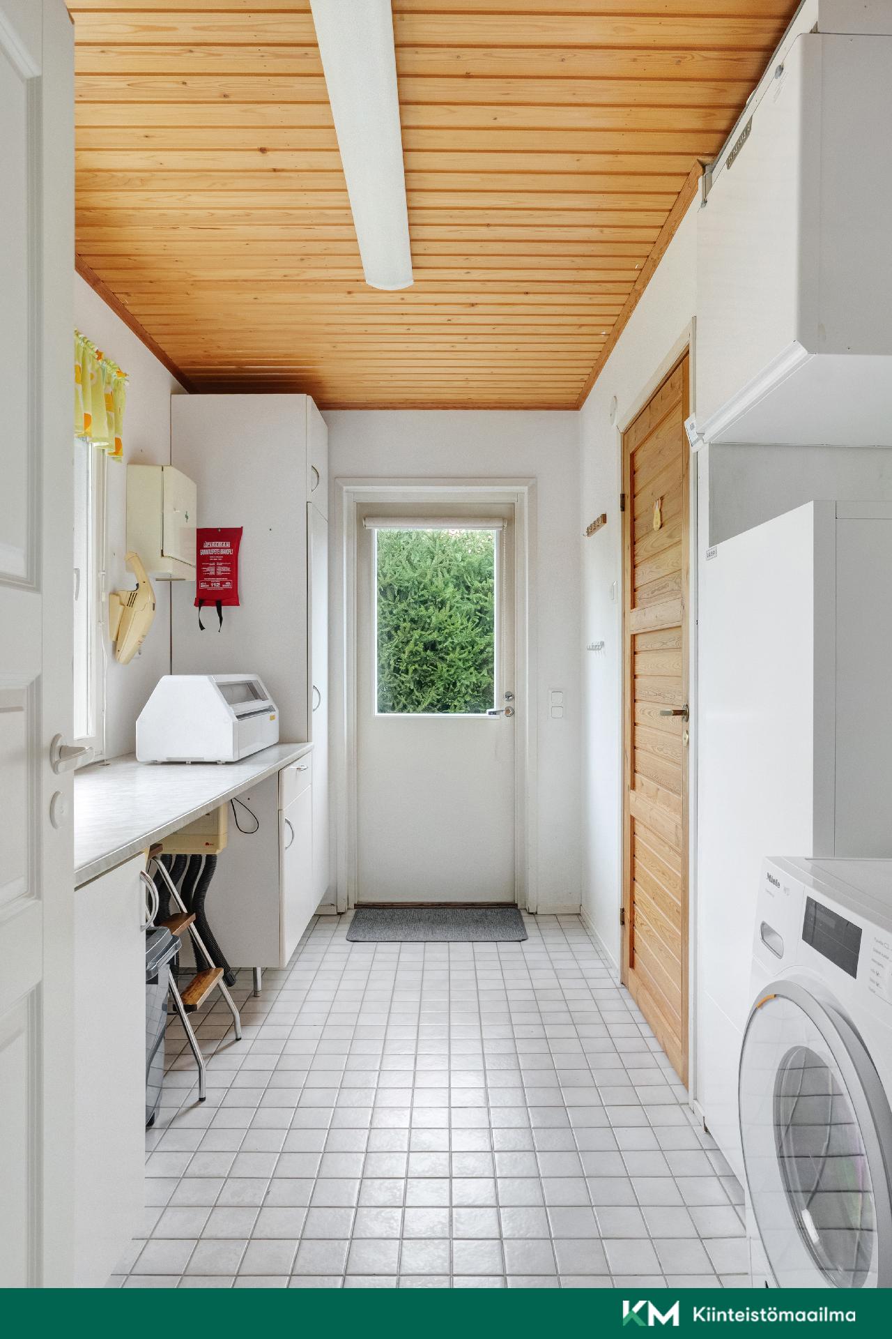 Kodinhoitohuone on tilavam ja siellä on myös yksi sisäänkäynti.