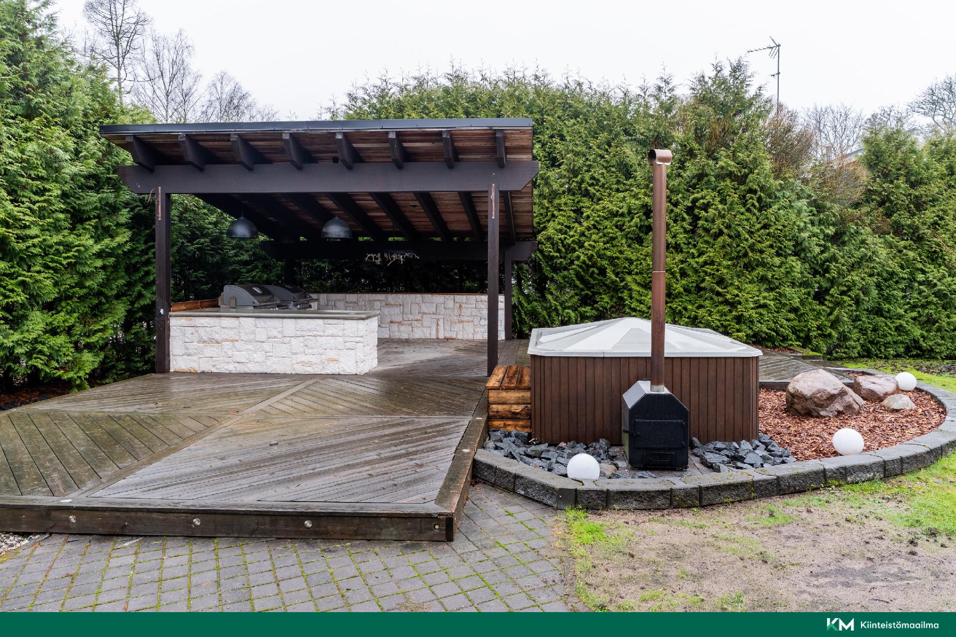 Kesäterasilla grillikatos ja puulämmitteinen palju