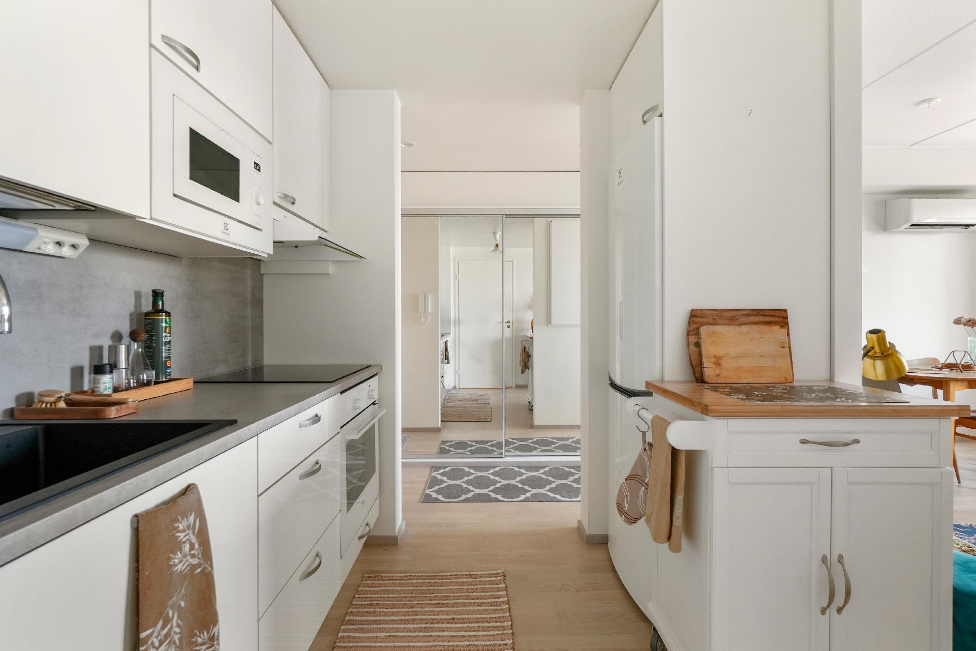 Vaaleaan keittiöön särmää tuovat tummanharmaa työtaso ja komposiittiallas.