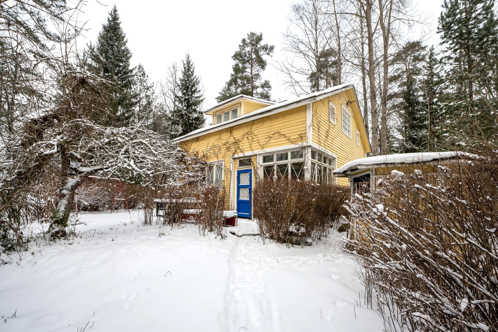 Huvilaa ympäröi puutarha, josta polku johtaa rantasaunalle.