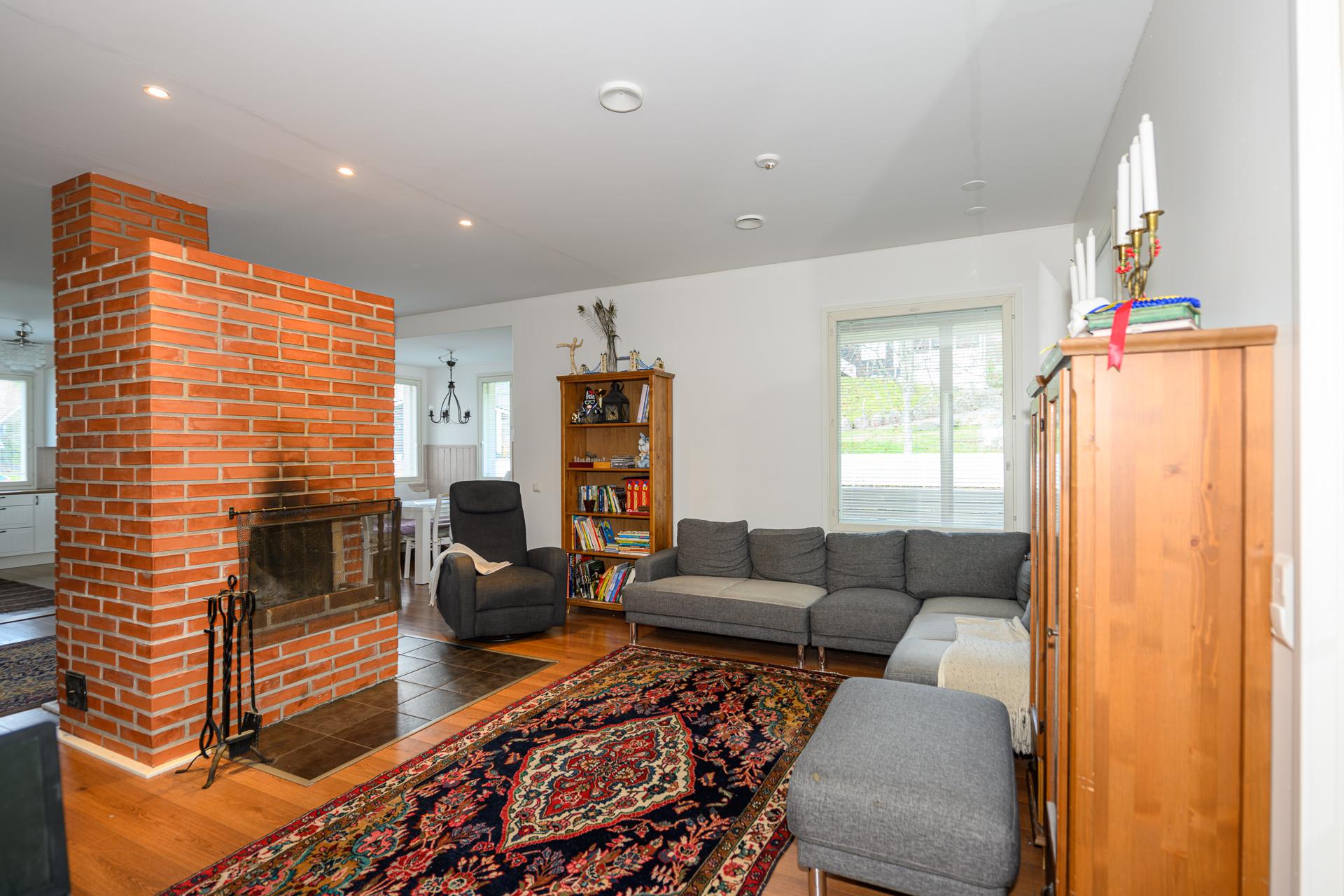 Kodin sydän on avoin oleskelualue: olohuone, ruokailutila ja keittiö. Varaava takka luo tunnelmaa ja tukee lämmityksessä. 