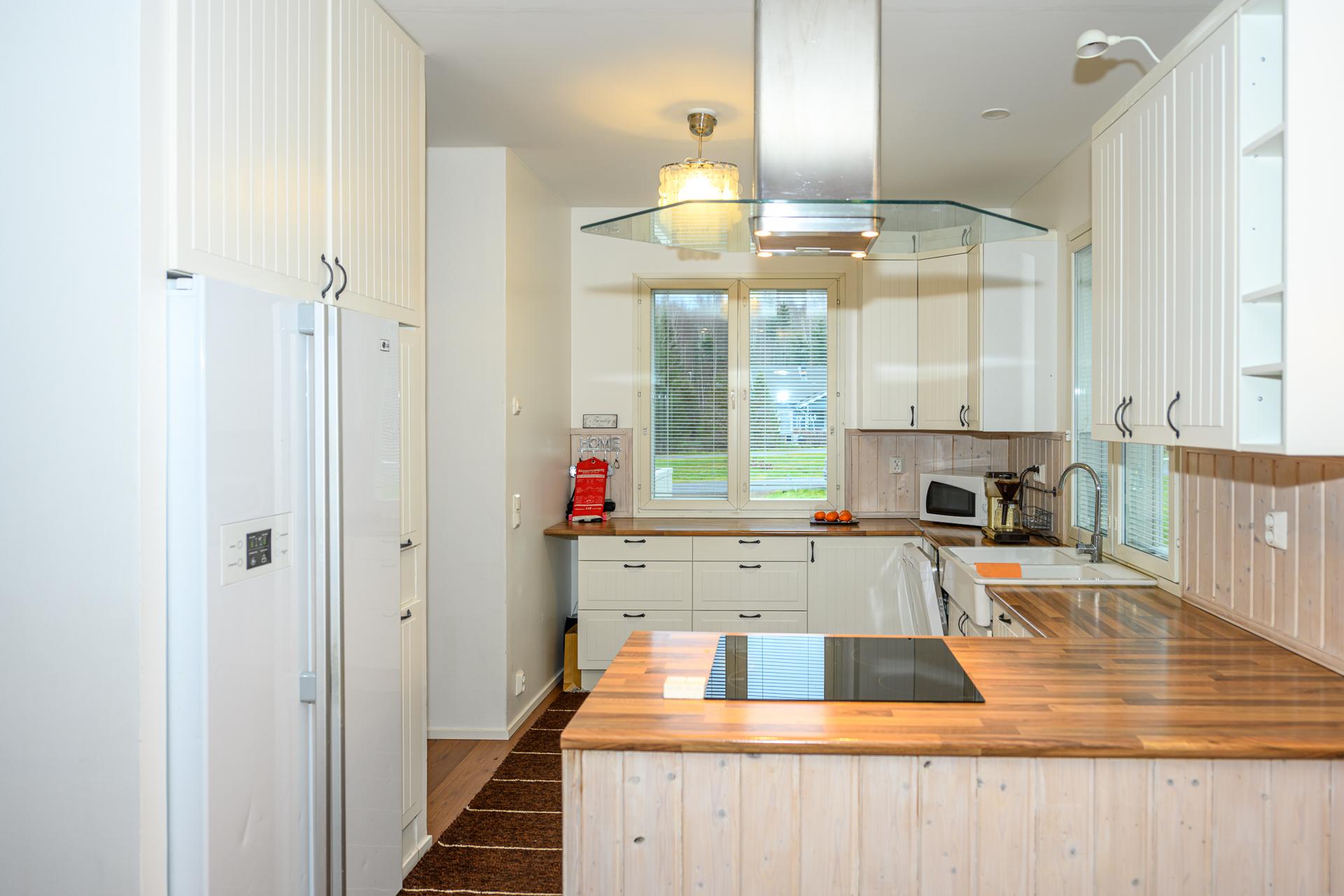 Vaaleasävyisessä keittiössä on jaoteltu toiminnot kätevästi neljälle seinämälle.