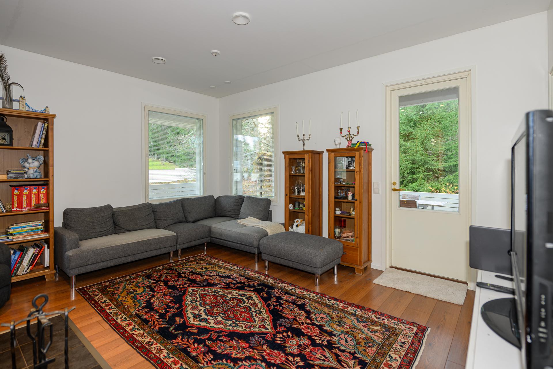 Olohuoneeseen persoonallista ilmettä antavat kulmaikkunat, ovi johtaa terassille.