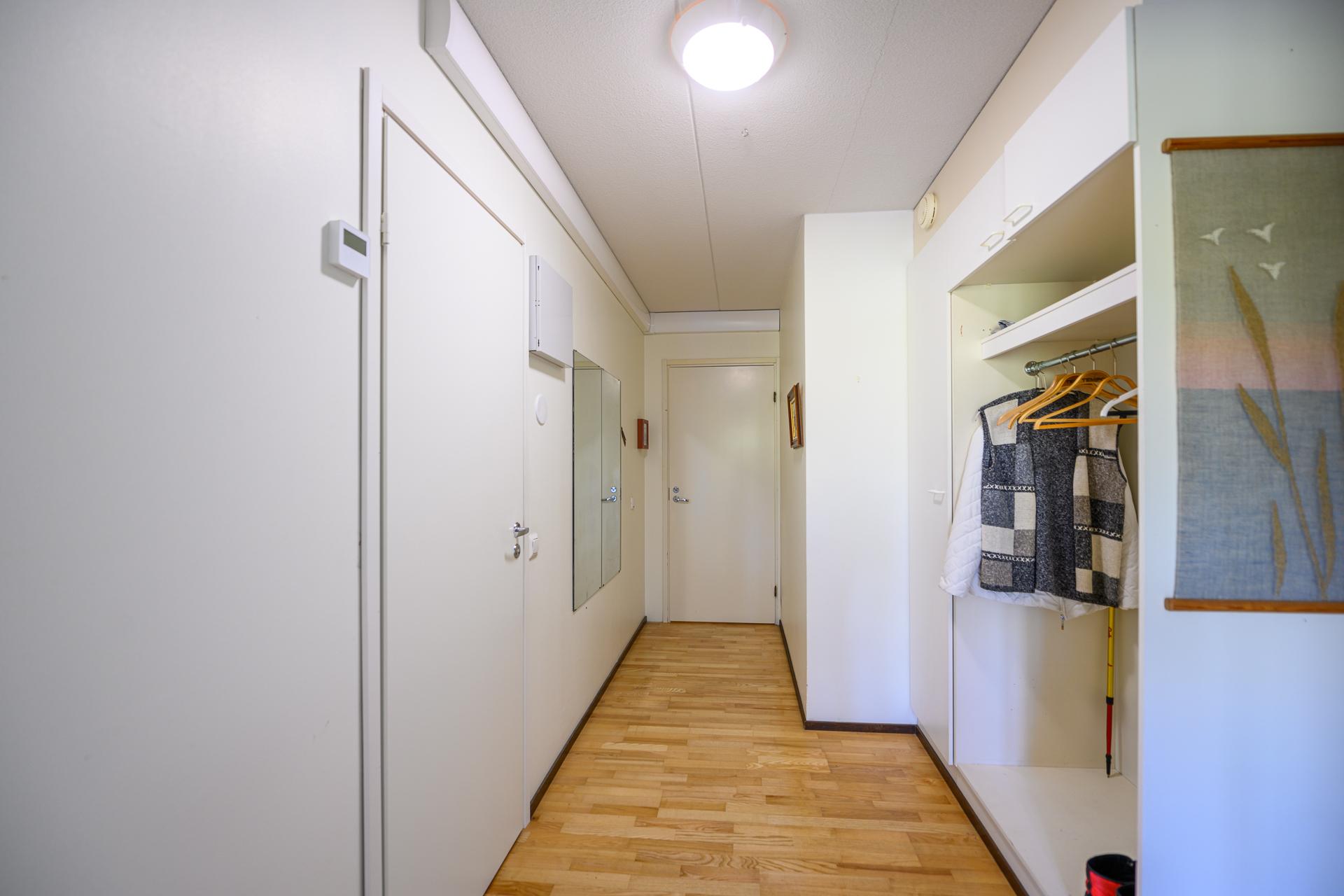 Näkymää keittiön suunnalta ulko-ovelle, vasemmalla ovi johtaa kylpyhuoneeseen ja oikealla eteisen vaatesäilytys.