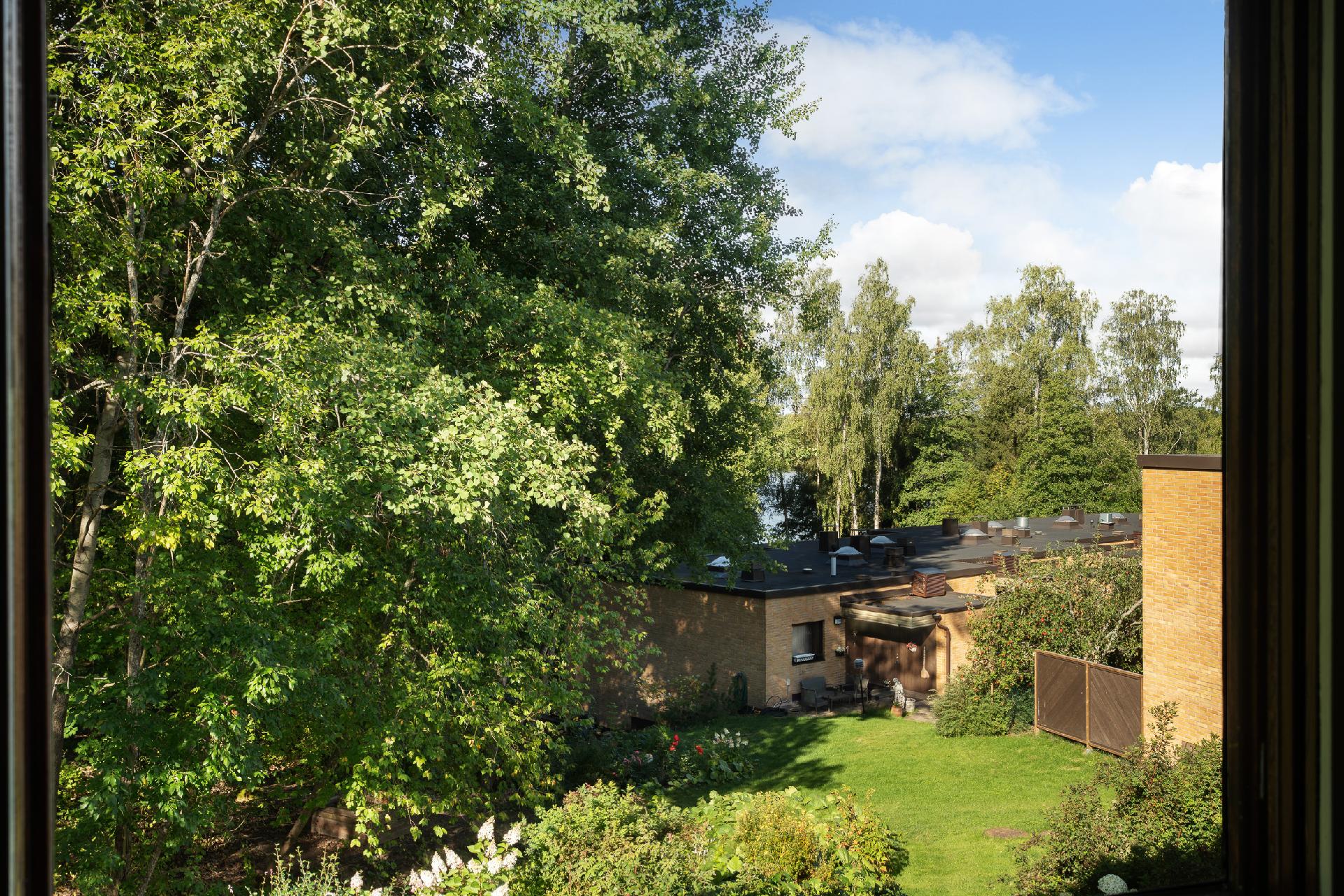 Maisema makuuhuoneen ikkunasta katsoen, puiden lomassa siintää Lippajärvi