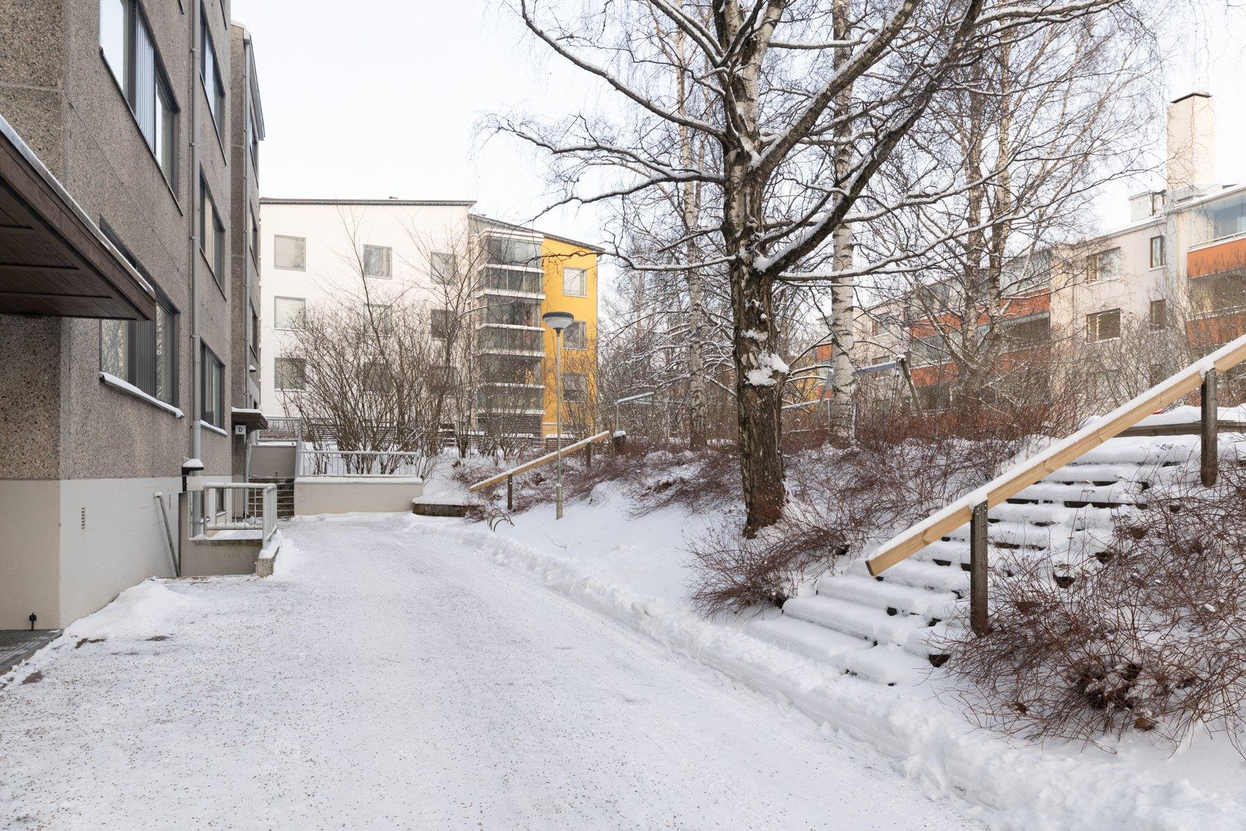 Taloyhtiön piha-aluetta - talon päädyssä on käynti saunaan ja uima-allasosastolle