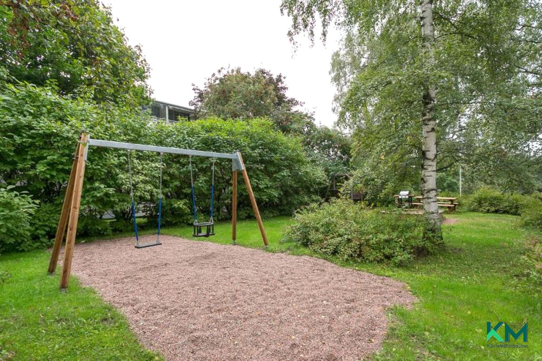 Taloyhtiön piha-aluetta - lasten keinut ja leikkipaikka, kesäkuva