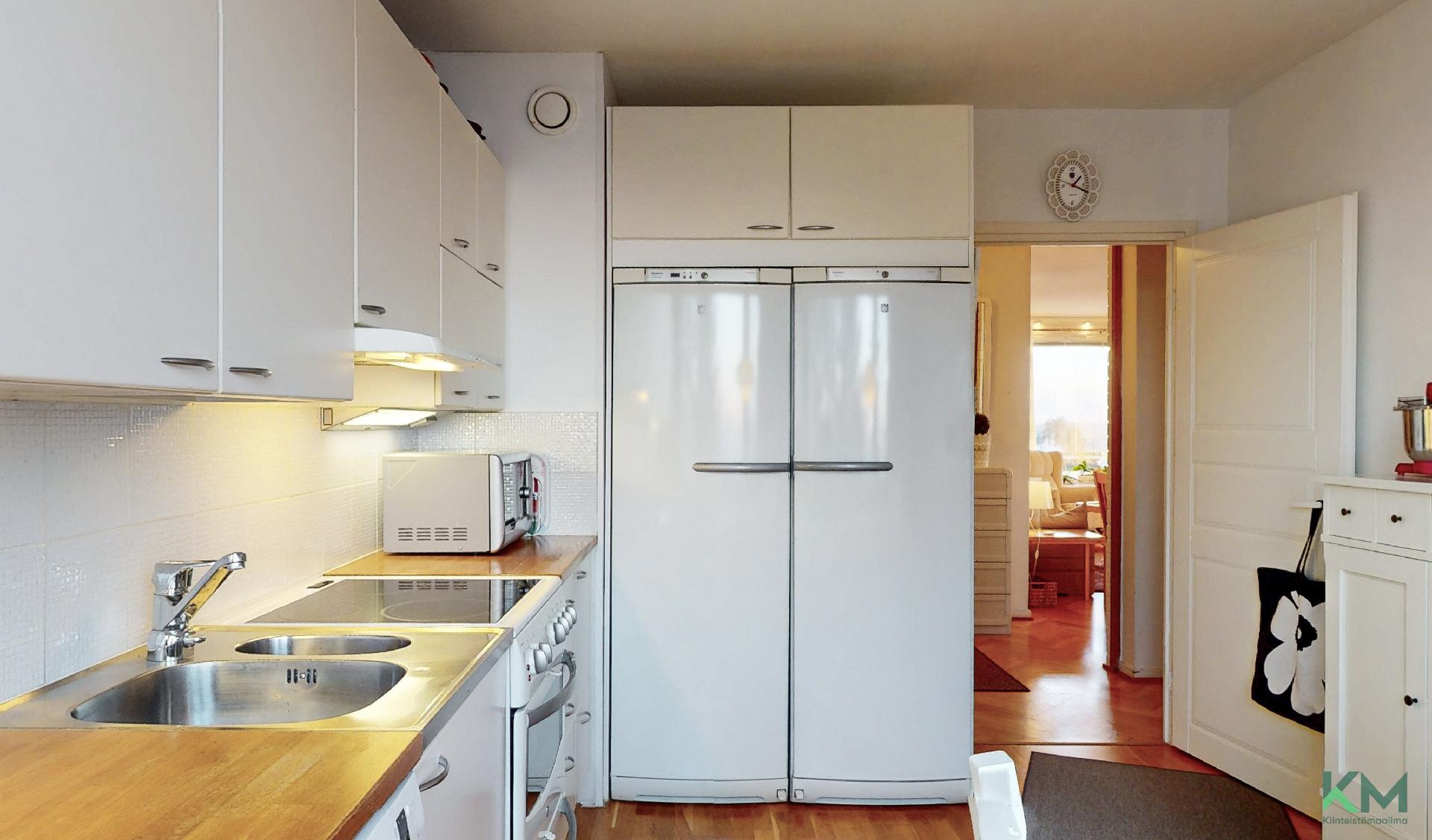 Keittiössä täysikorkeat jääkaappi ja pakastin