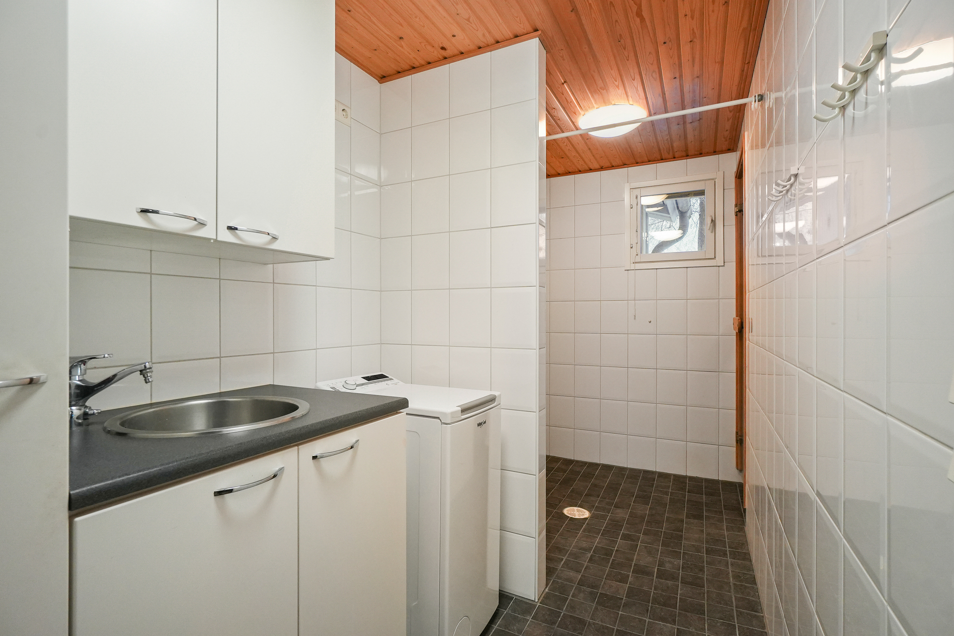 Yhdistetty kodinhoito- ja kylpyhuonetila sekä sauna.