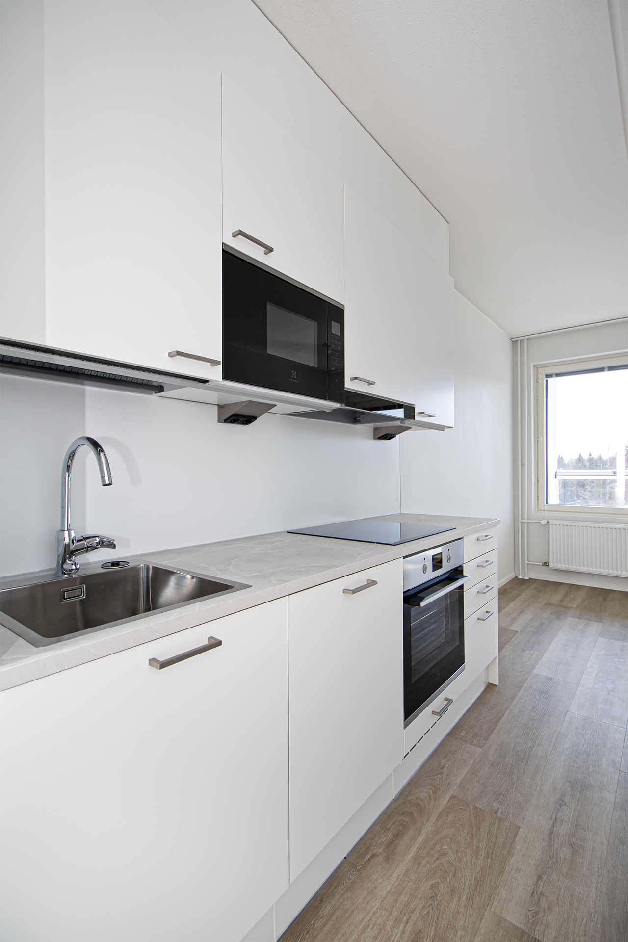 Vaalea keittiö ja vaaleat vinyylilattiat muodostavat raikkaan kokonaisuuden.