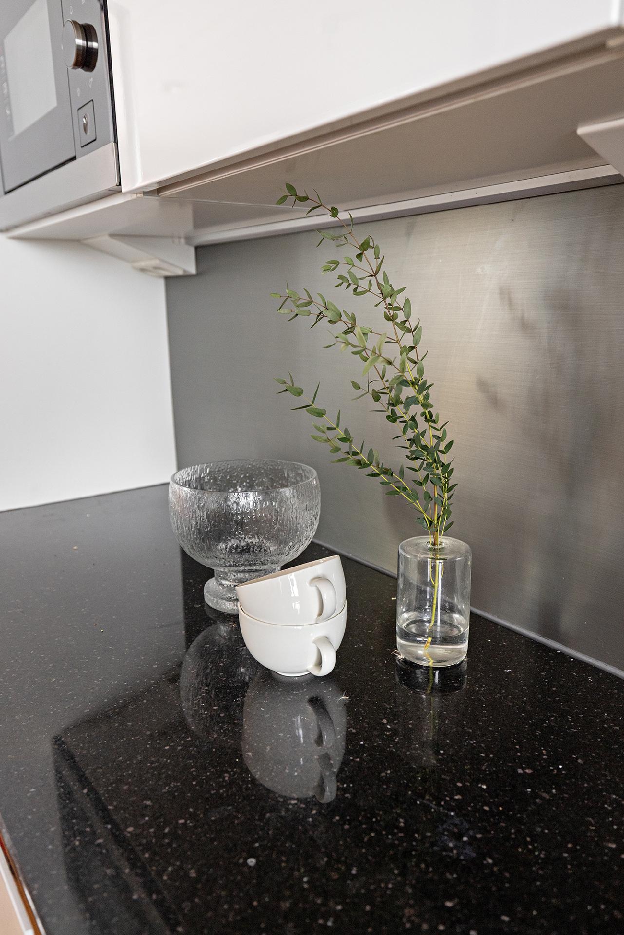 Keittiössä tyylikkäät mustat kivitasot ja helppohoitoinen välitila