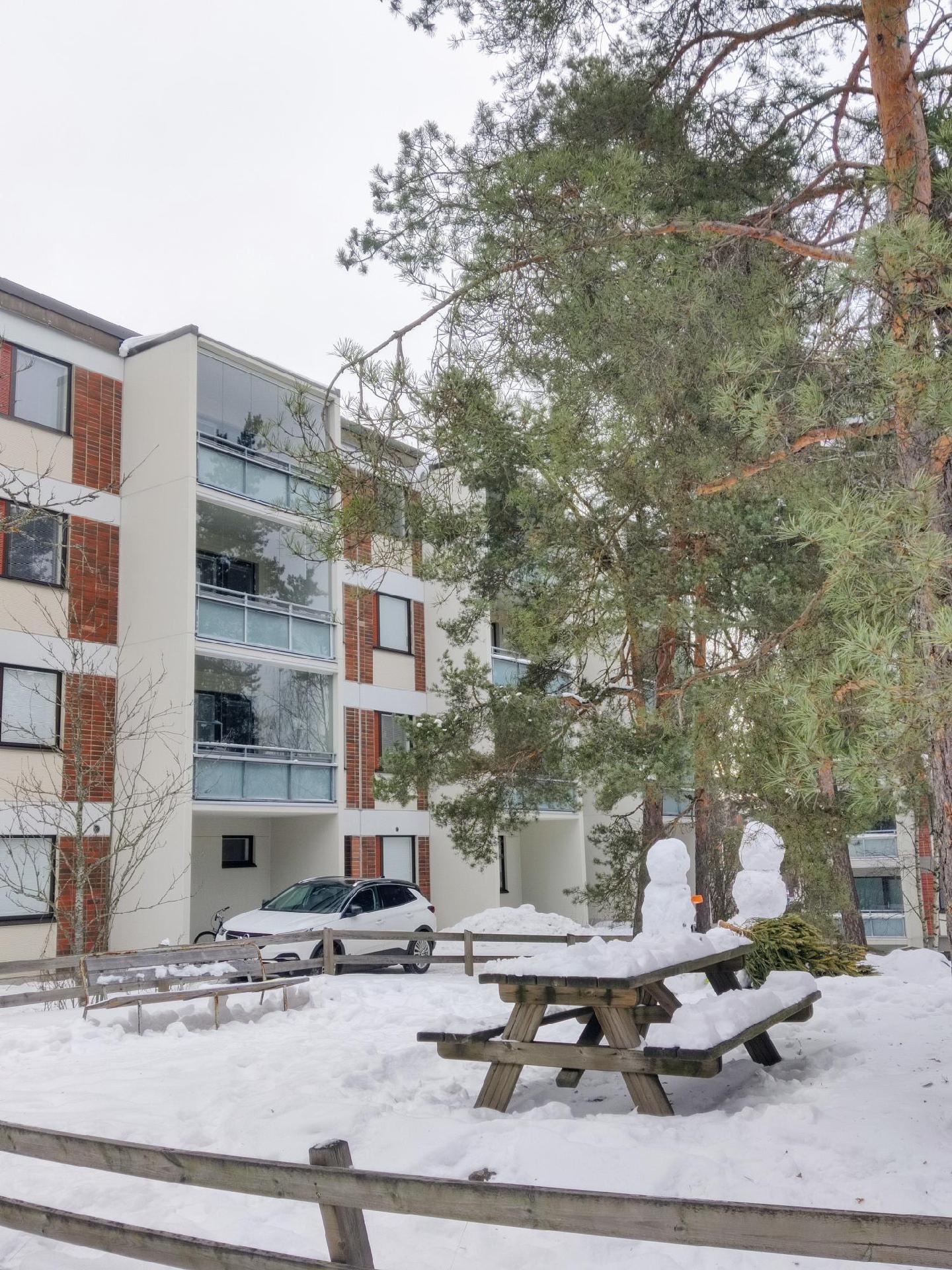 Asunnon parveke on männyn takana, ylin kerros.