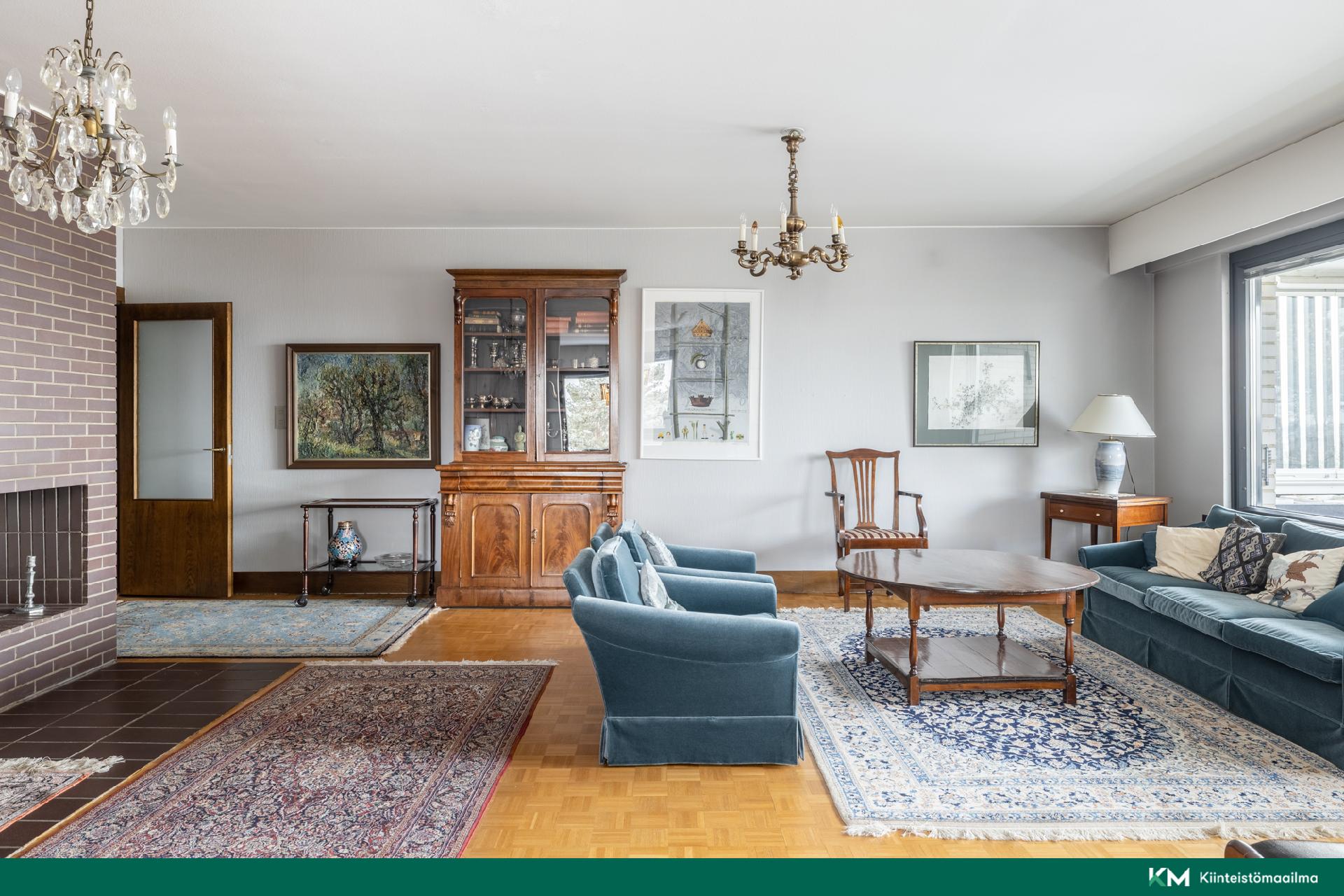  Avara ja elegantti olohuone, jossa takka ja kauniit materiaalit korostavat tämän hyvin hoidetun kodin laatua ja viihtyisyyttä