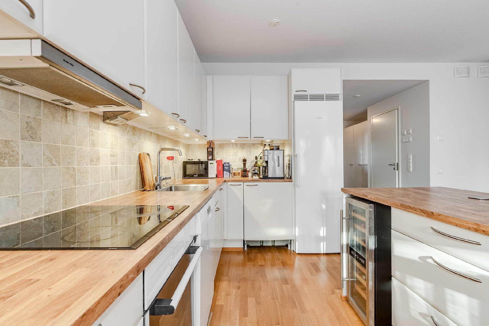 Vaalea saarekekeittiö, jossa on hyvin kaappitilaa