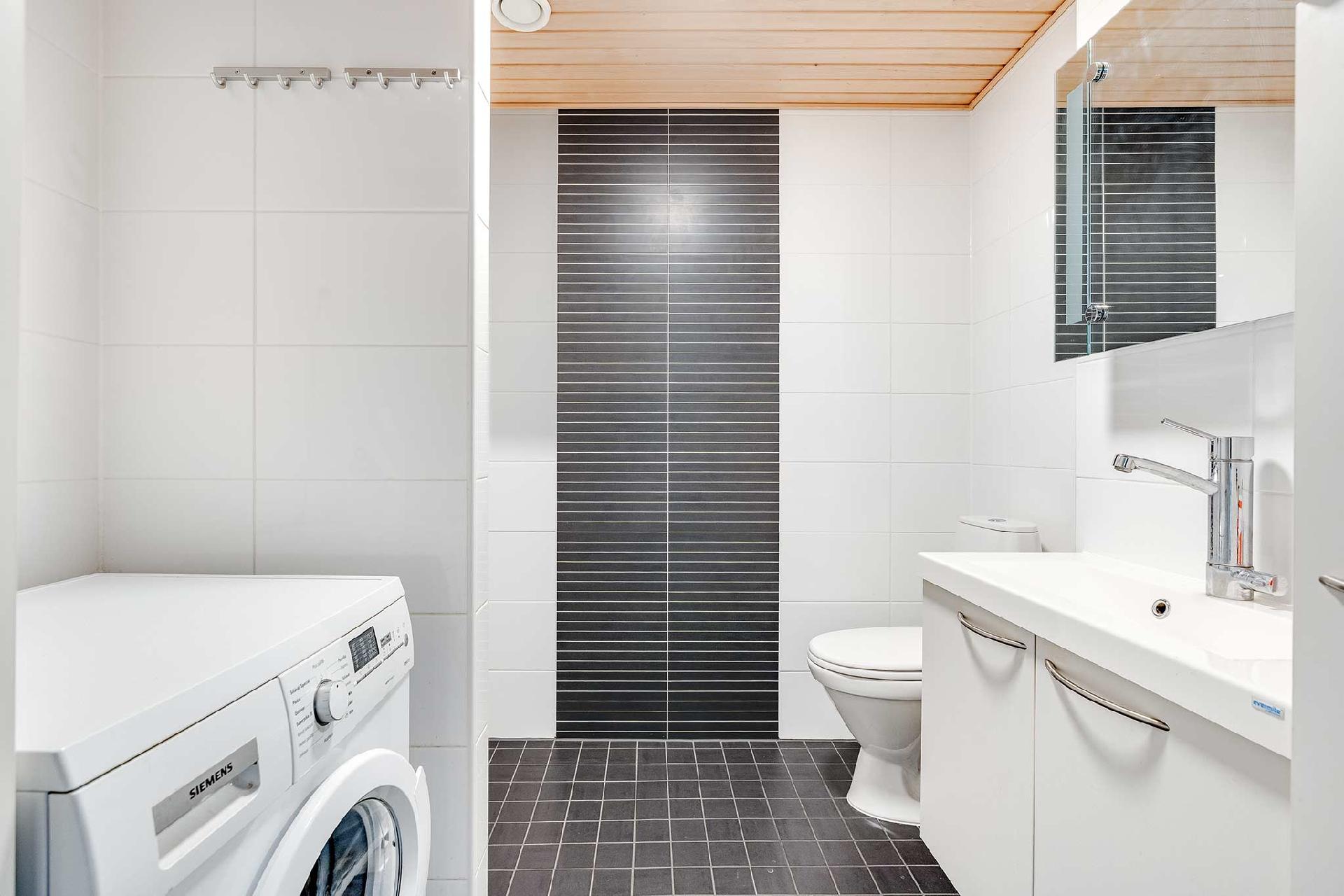 Yläkerran kylpyhuoneessa on kodinhoitotila ja paikka pesutornille