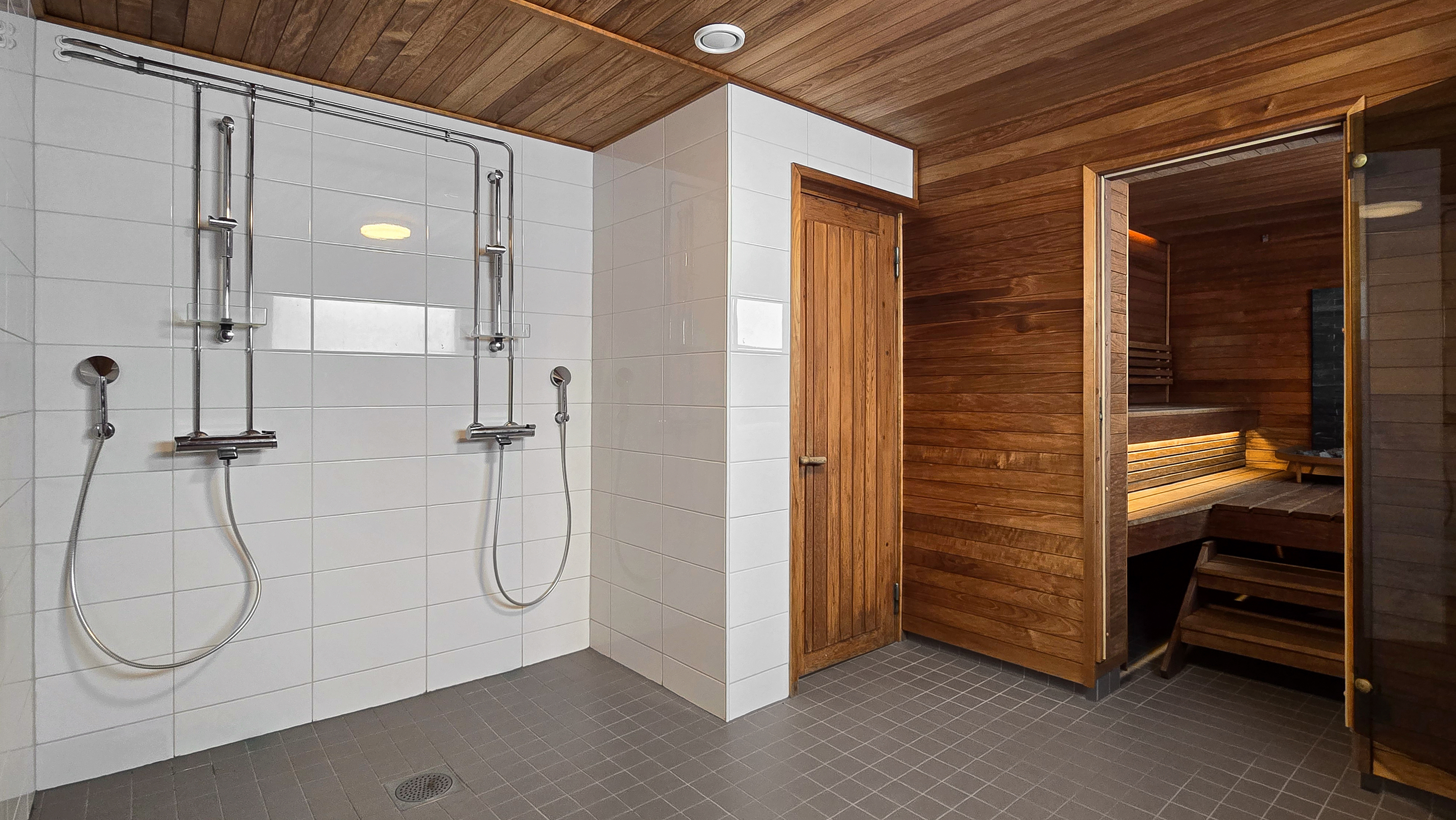 Saunarakennuksen kylpyhuoneessa kaksi suihkua