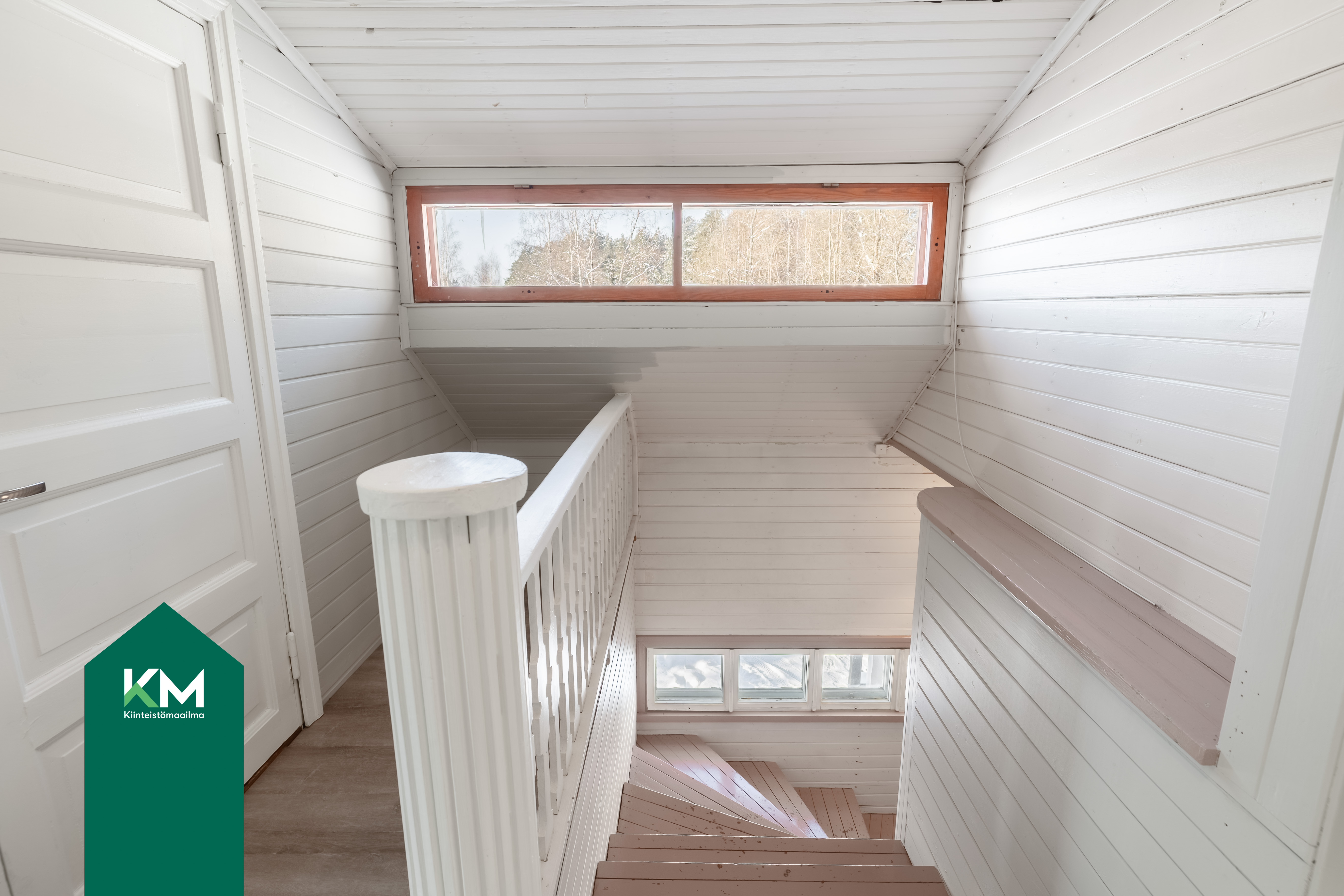 Yläkerran portaikko on valoisa. Vasemmalla ovi vaatehuoneeseen.